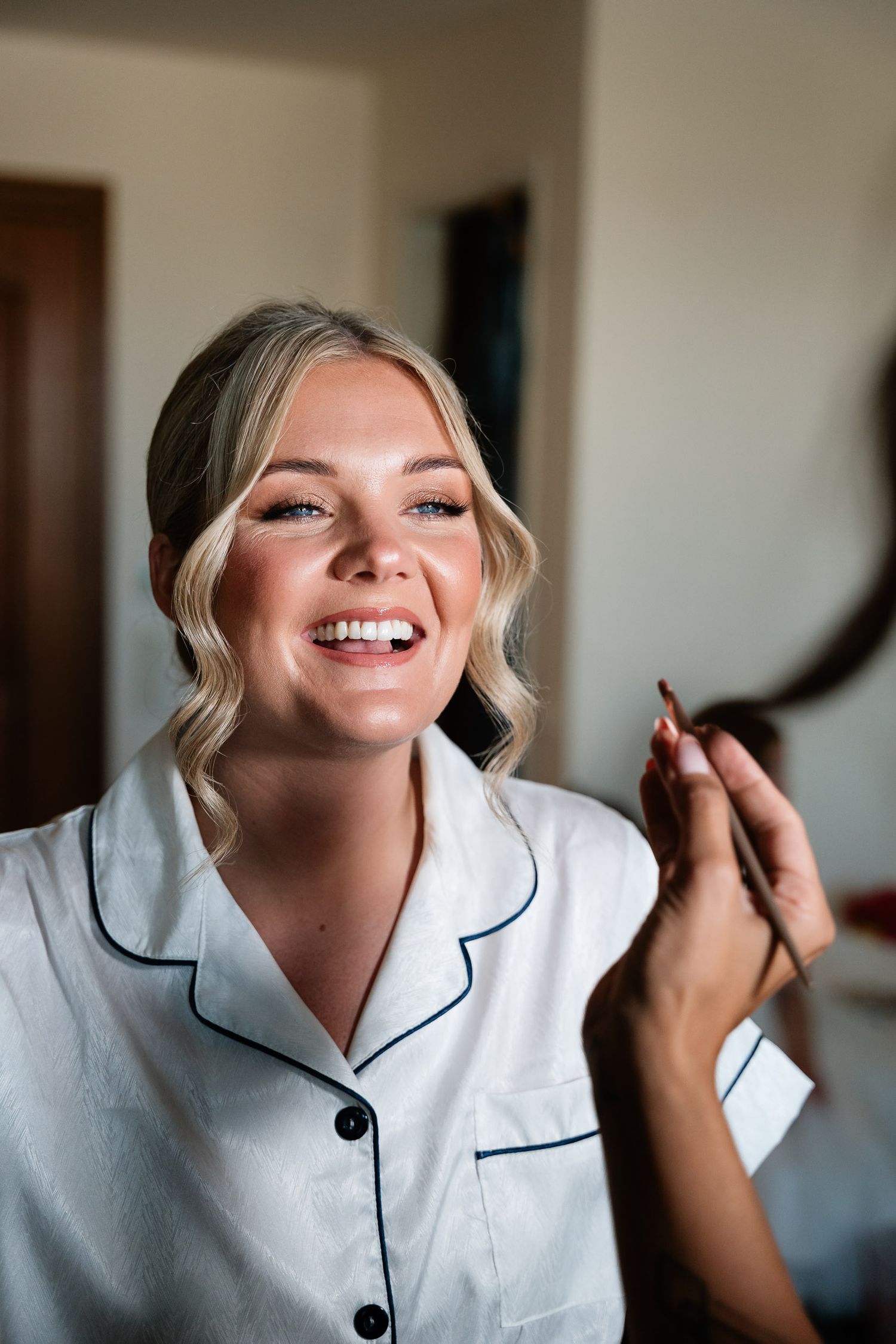 A series of four photos showing someone in a white collared pajama top getting their makeup professionally applied.