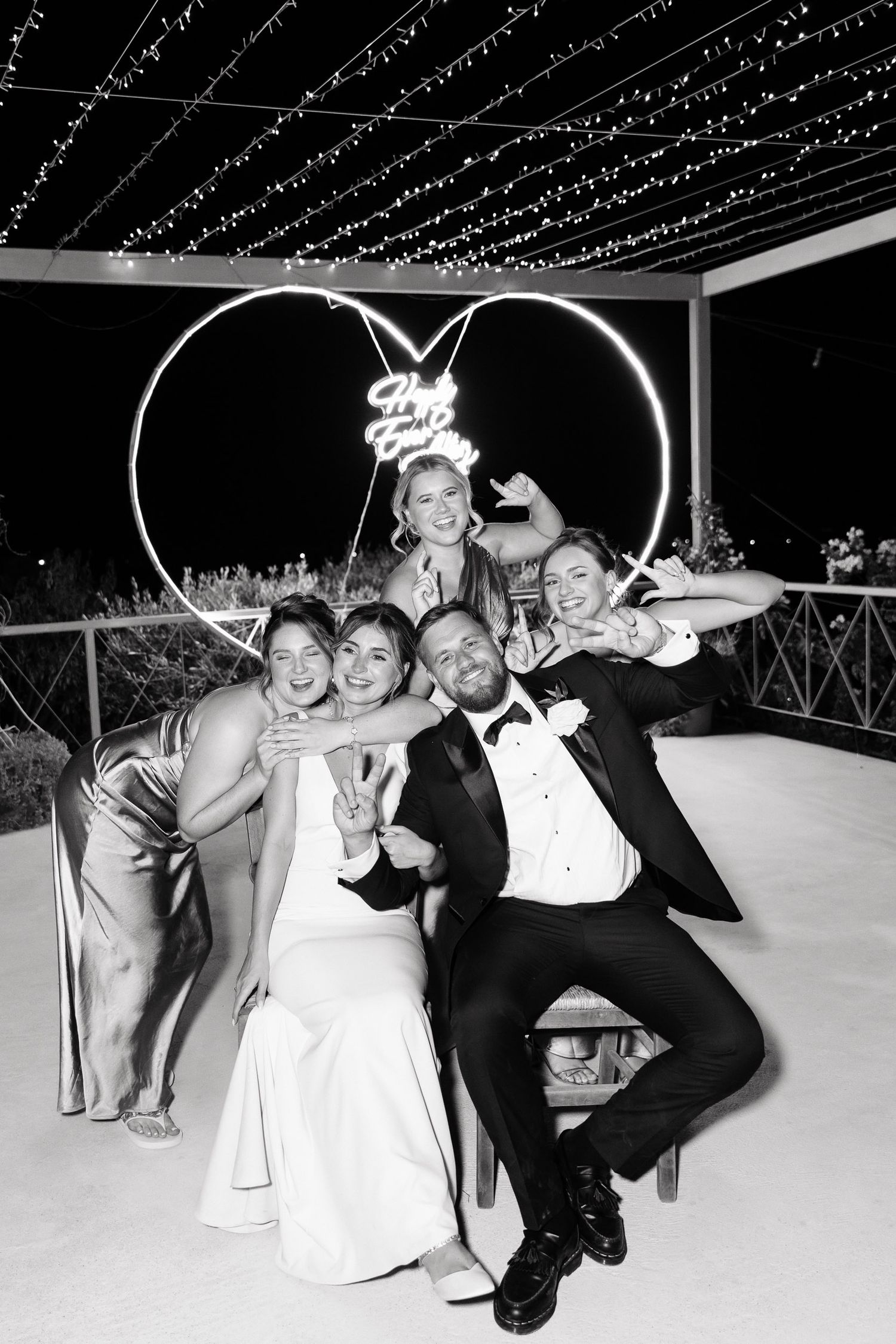 Black and white photo series showing wedding party members posing playfully on a dance floor under twinkling lights.