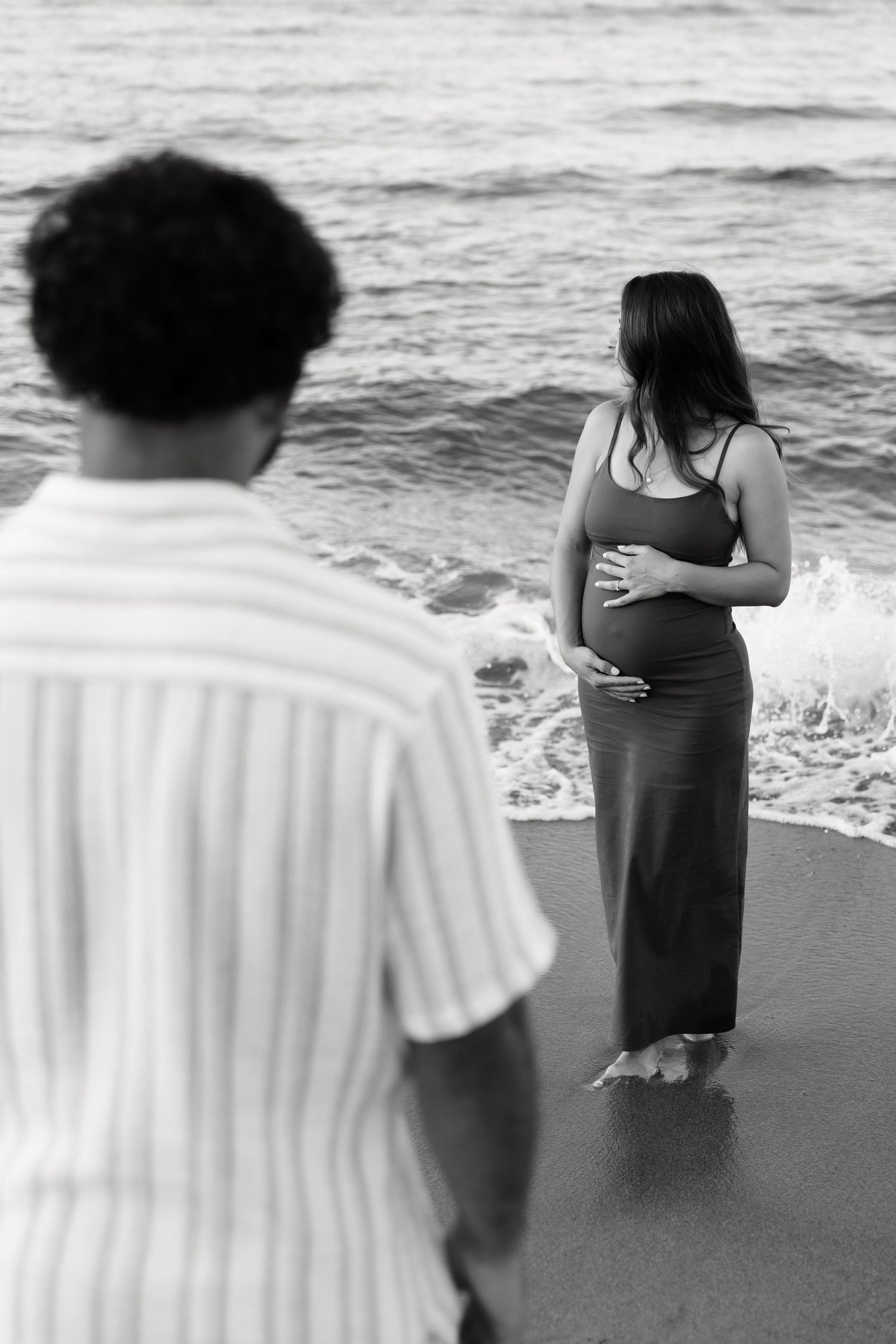 A black and white photo series shows people walking along a beach shoreline with waves and white towels.