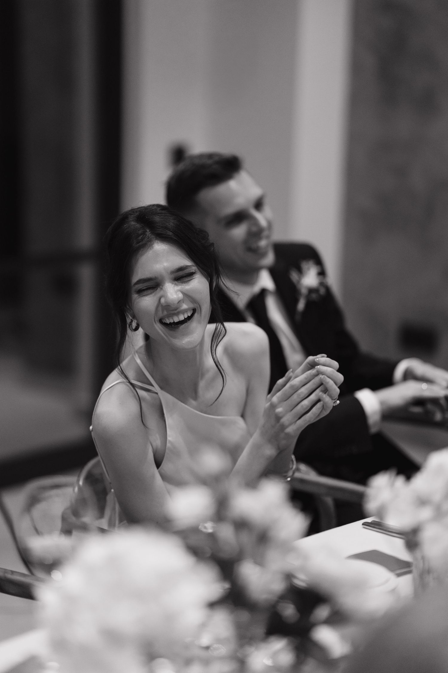 A candid black and white photo sequence showing joyful laughter during a wedding reception.