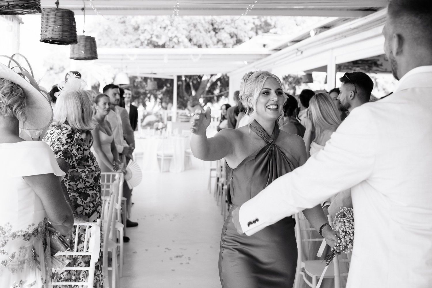 People dancing and socializing at an outdoor event with hanging lights and a festive atmosphere captured in black and white.