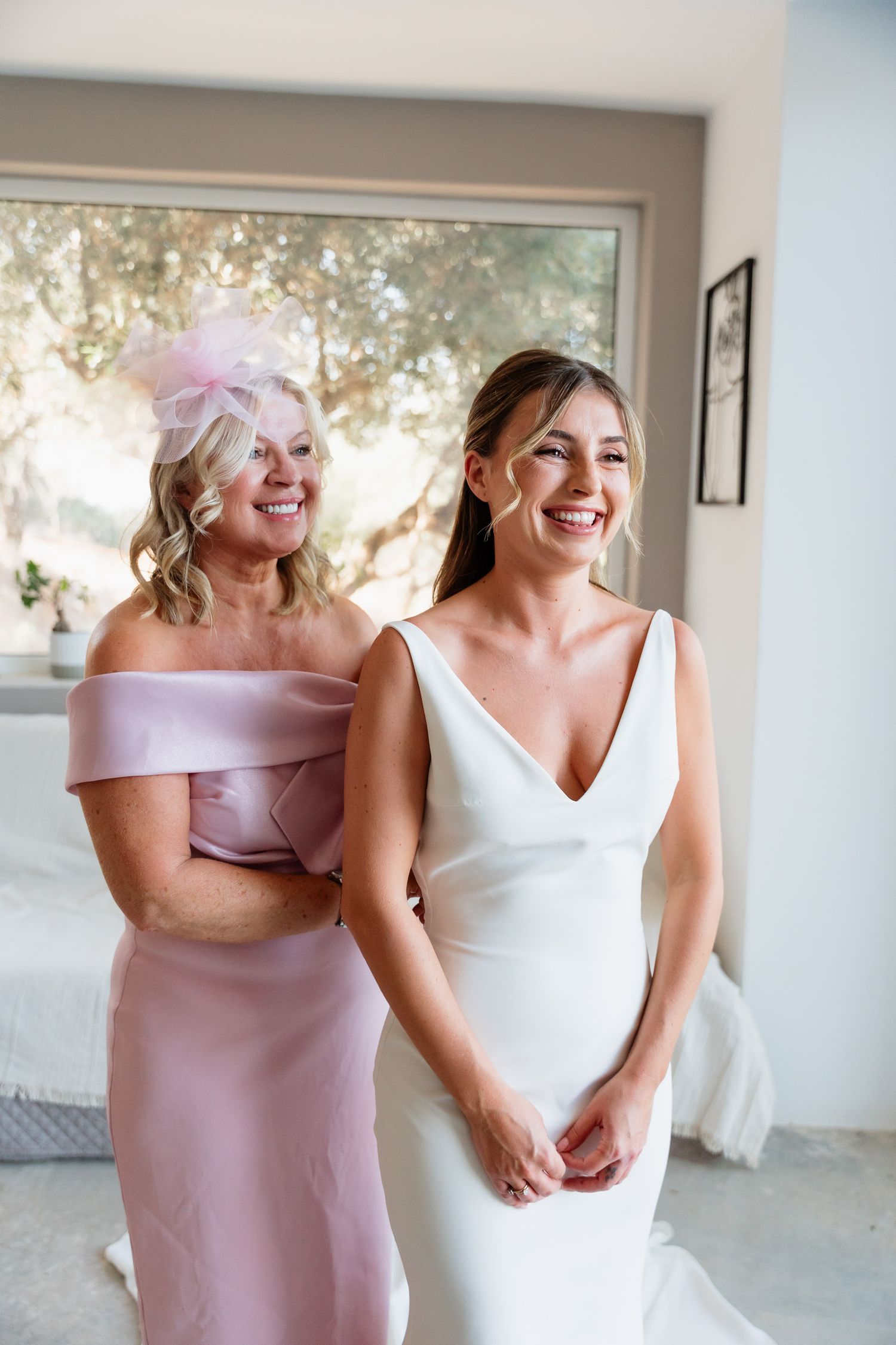 Candid moments of laughter and joy shared between women in pink bridesmaid dresses and white wedding gown at an indoor venue.