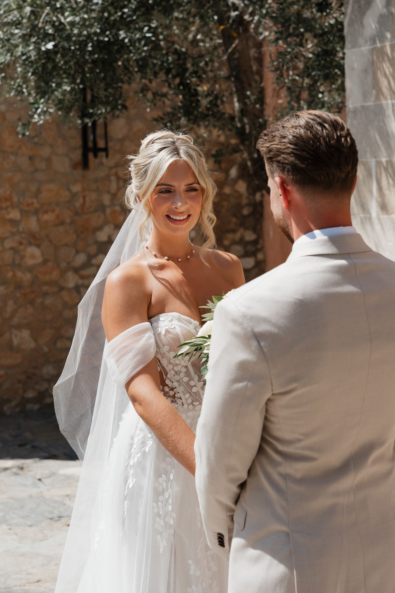 A bride and groom share a tender moment during their first look, captured in a sequence of candid photos against a brick wall.