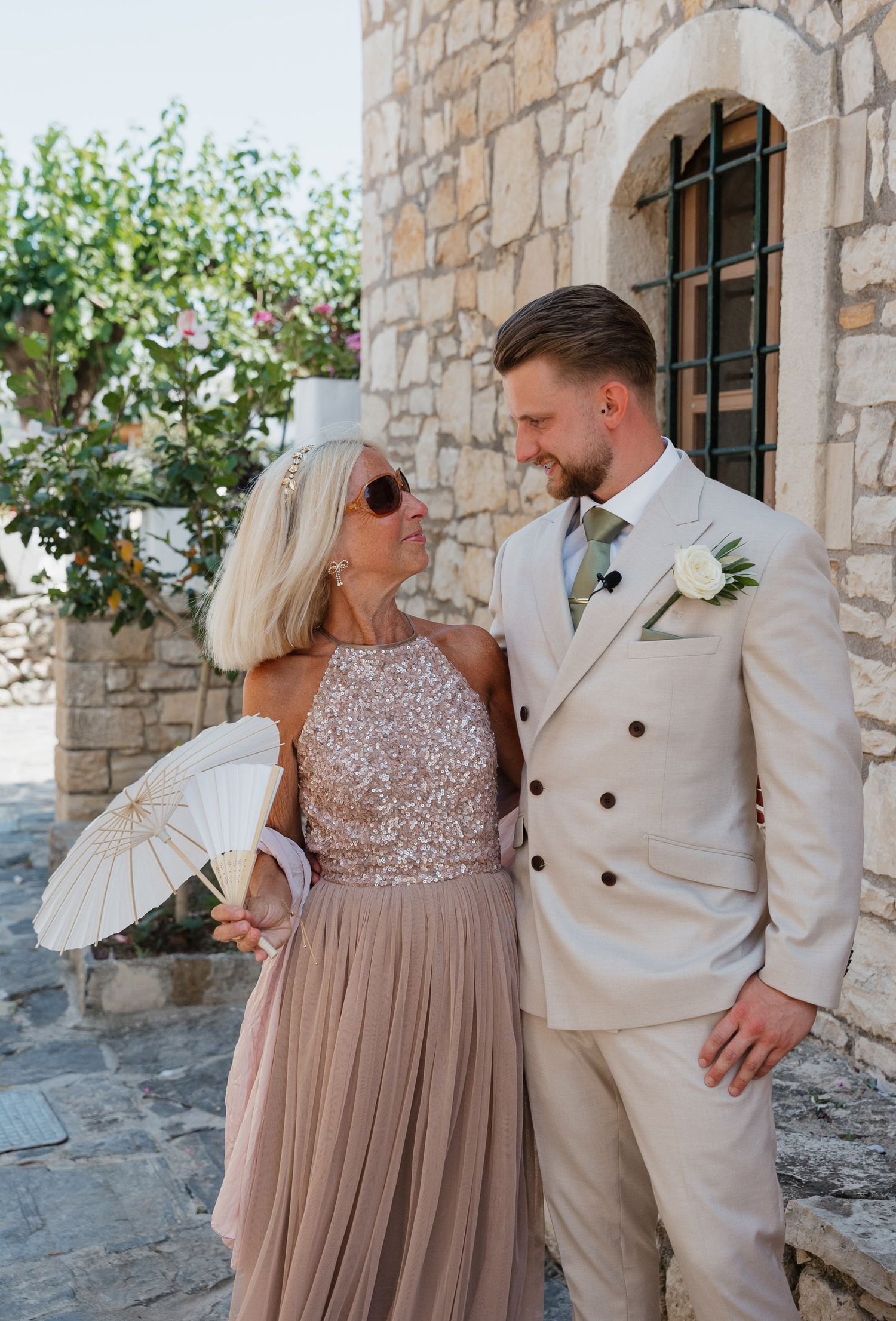 A couple in formal attire share tender moments against a rustic stone wall backdrop in a series of romantic photos.