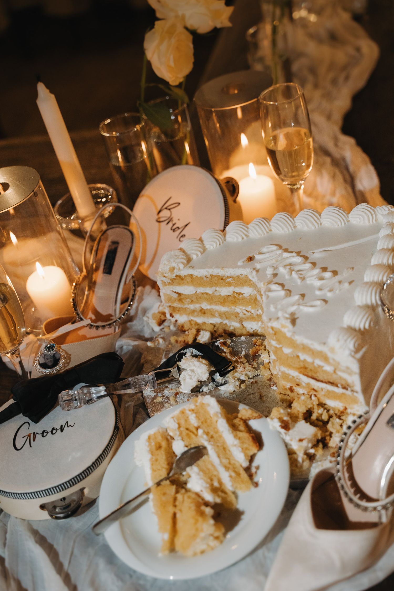 Messy plates with leftover cake and dessert crumbs illuminated by glowing candlelight at an elegant dinner table setting.