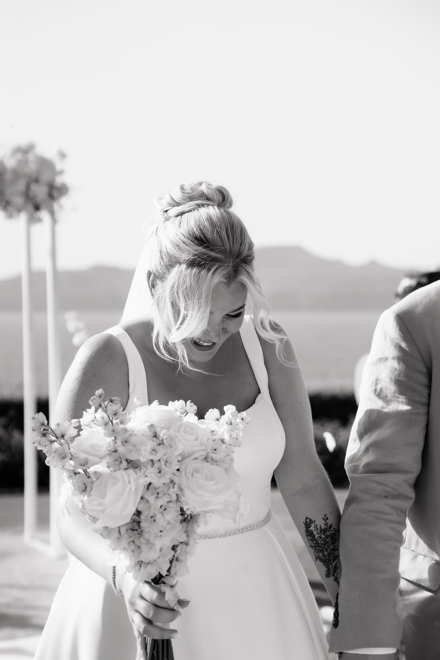 Black and white wedding photo sequence showing a bride laughing joyfully with her white floral bouquet outdoors.