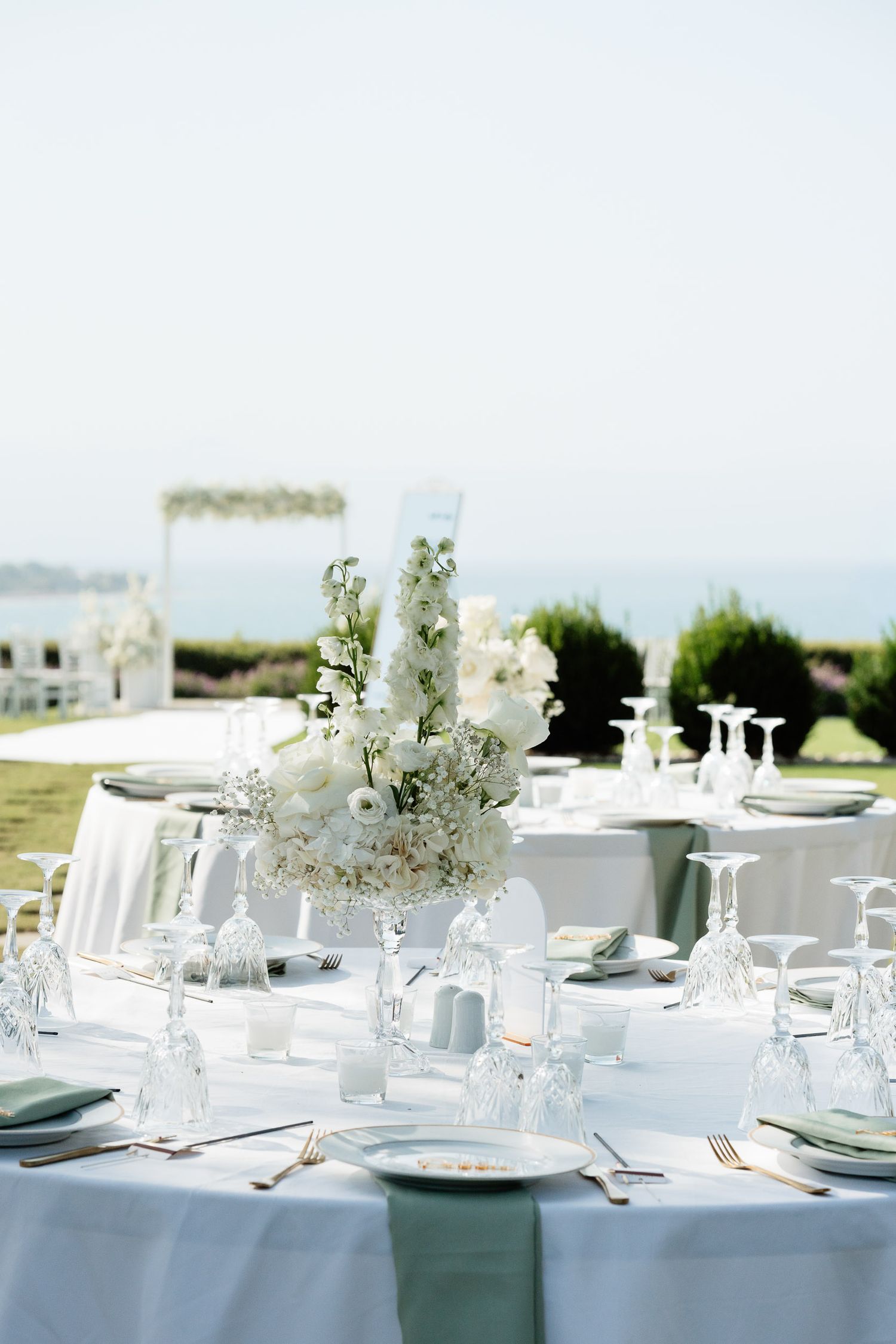 Elegant outdoor wedding reception tables decorated with white floral centerpieces and delicate place settings.