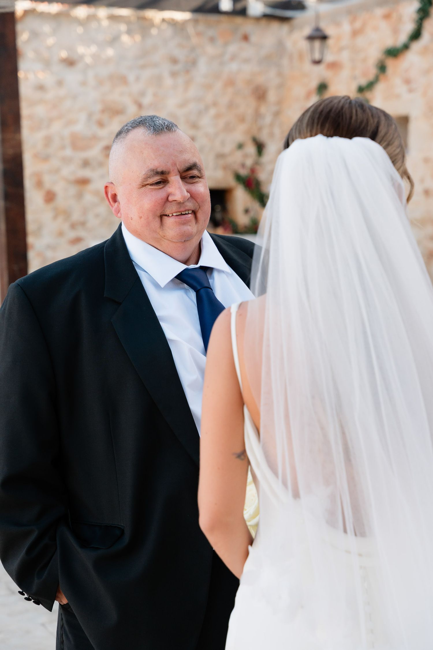 A bride and her father share an emotional first look moment in a series of candid photos at an outdoor venue.