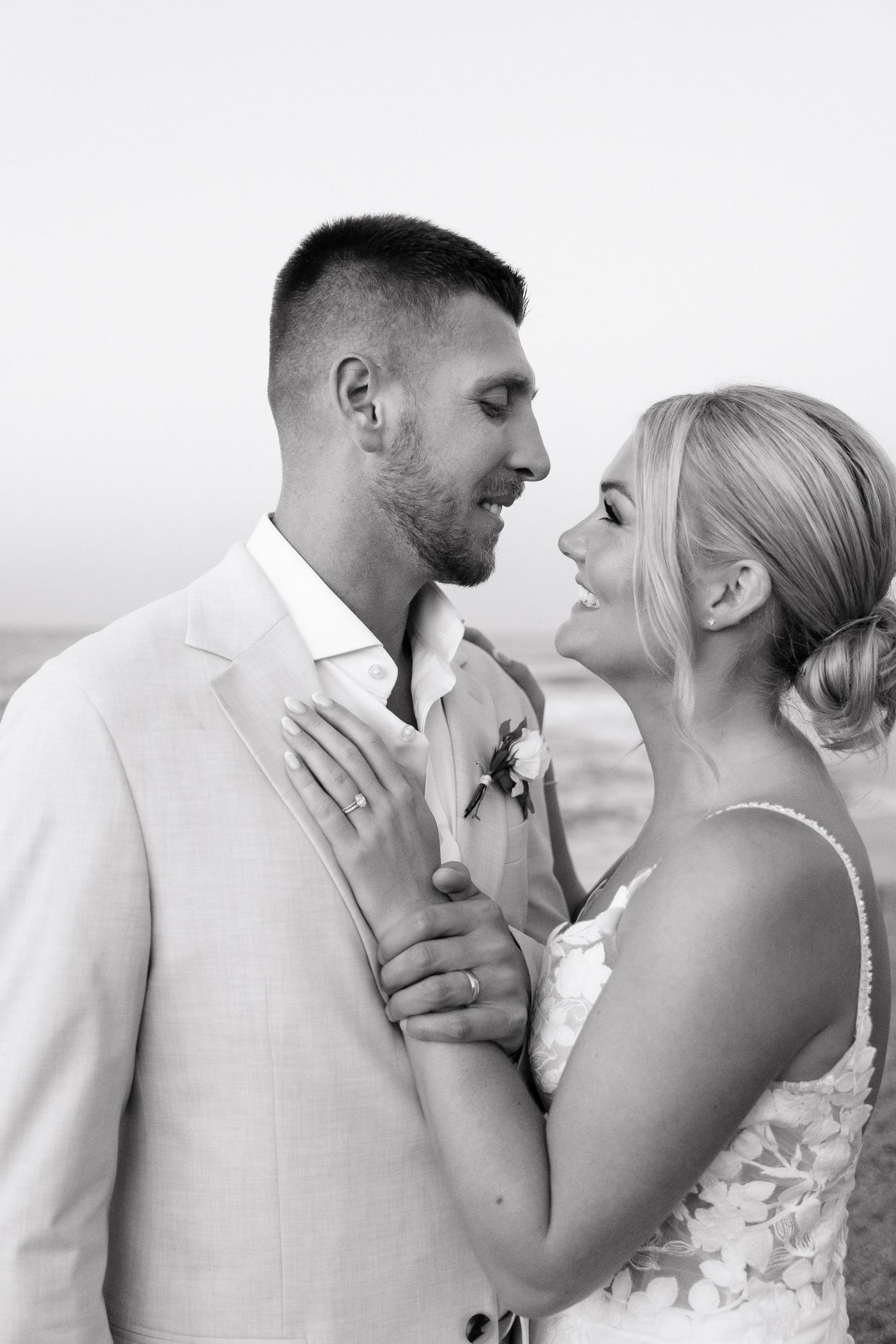 A romantic black and white wedding photo shows a couple in intimate embrace, with the bride in white and groom in light suit.