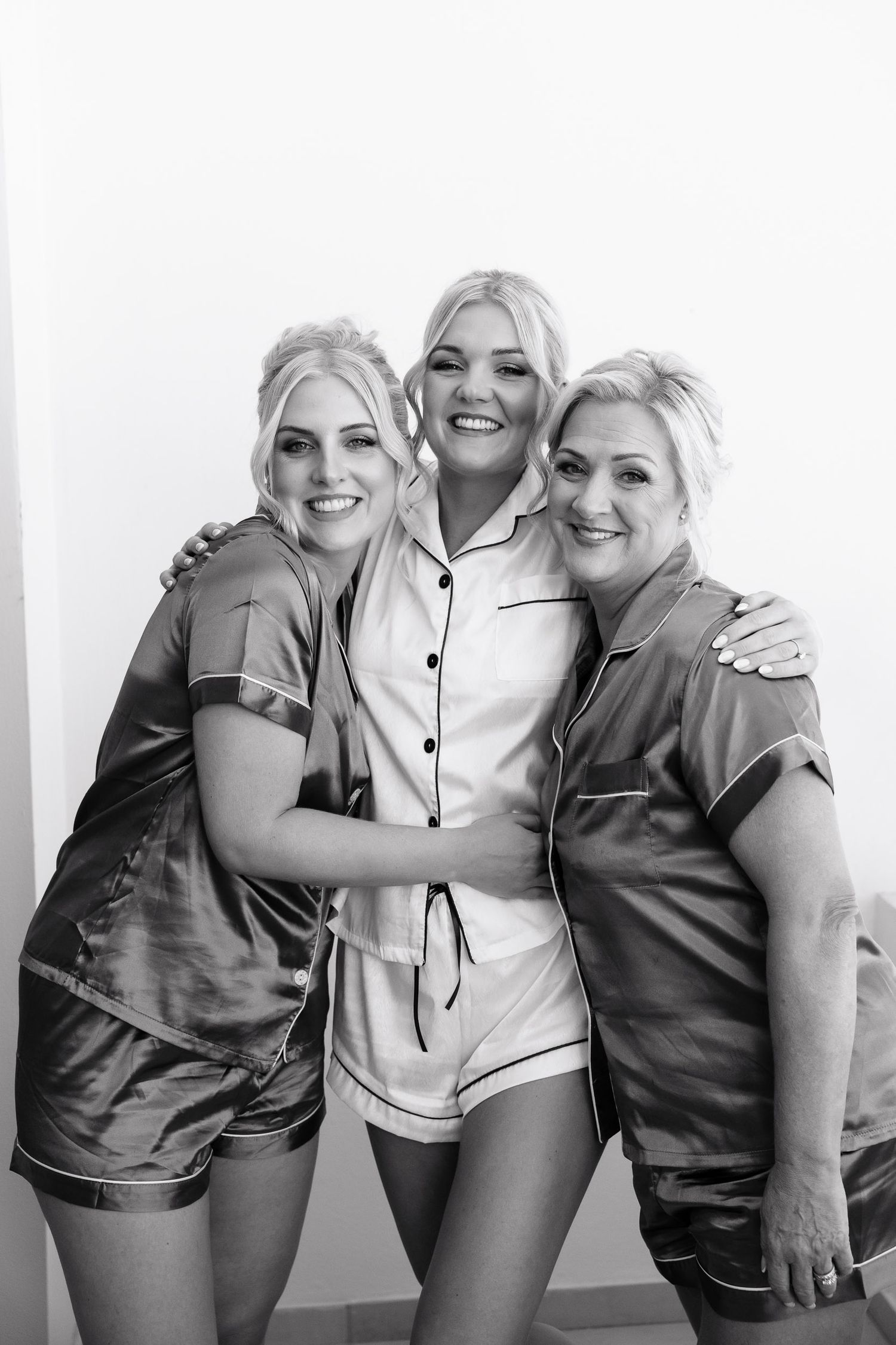 A series of black and white photos showing three people embracing and laughing together against a white background.