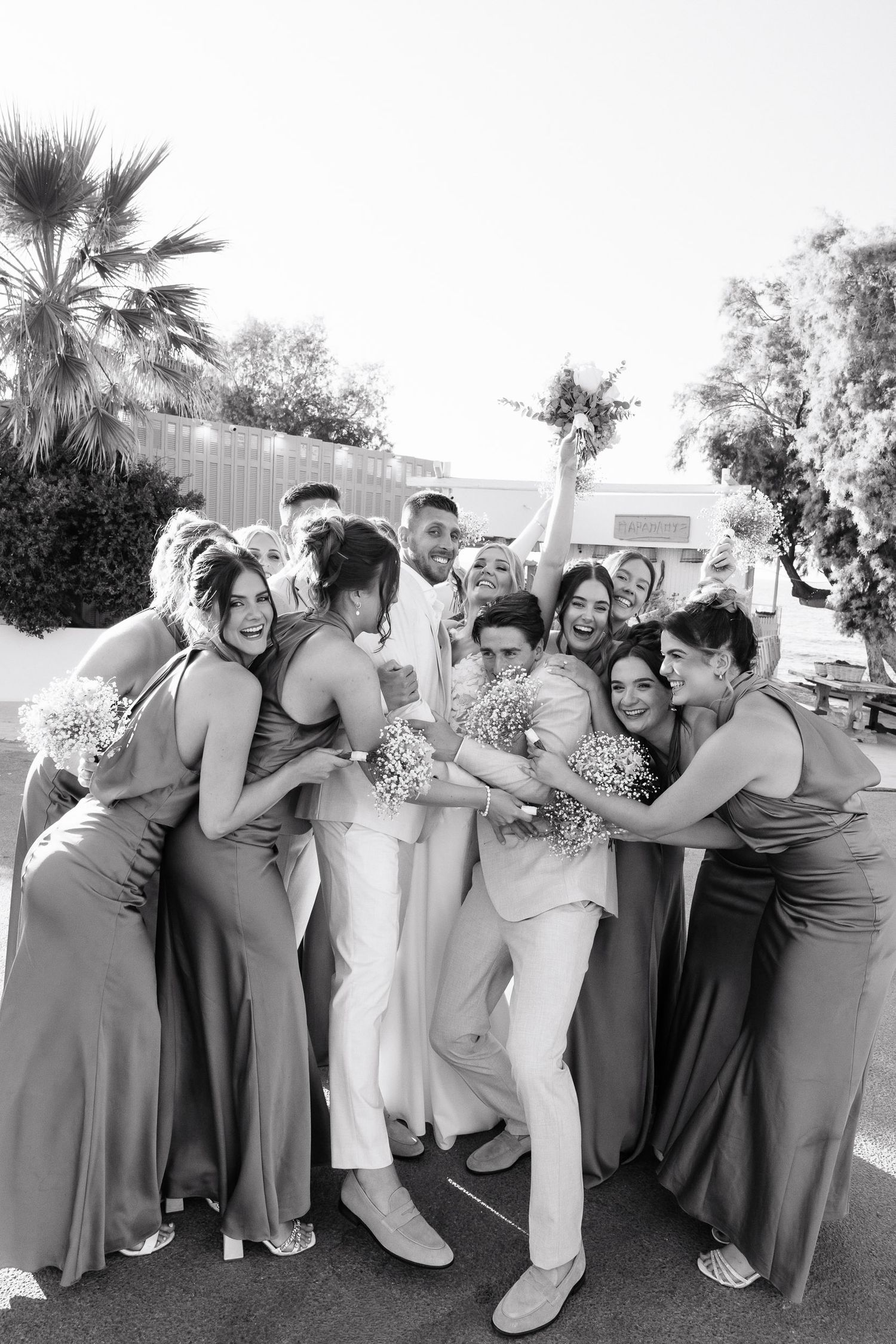 Wedding party members in gray dresses and white attire pose playfully in a candid photo series outdoors.
