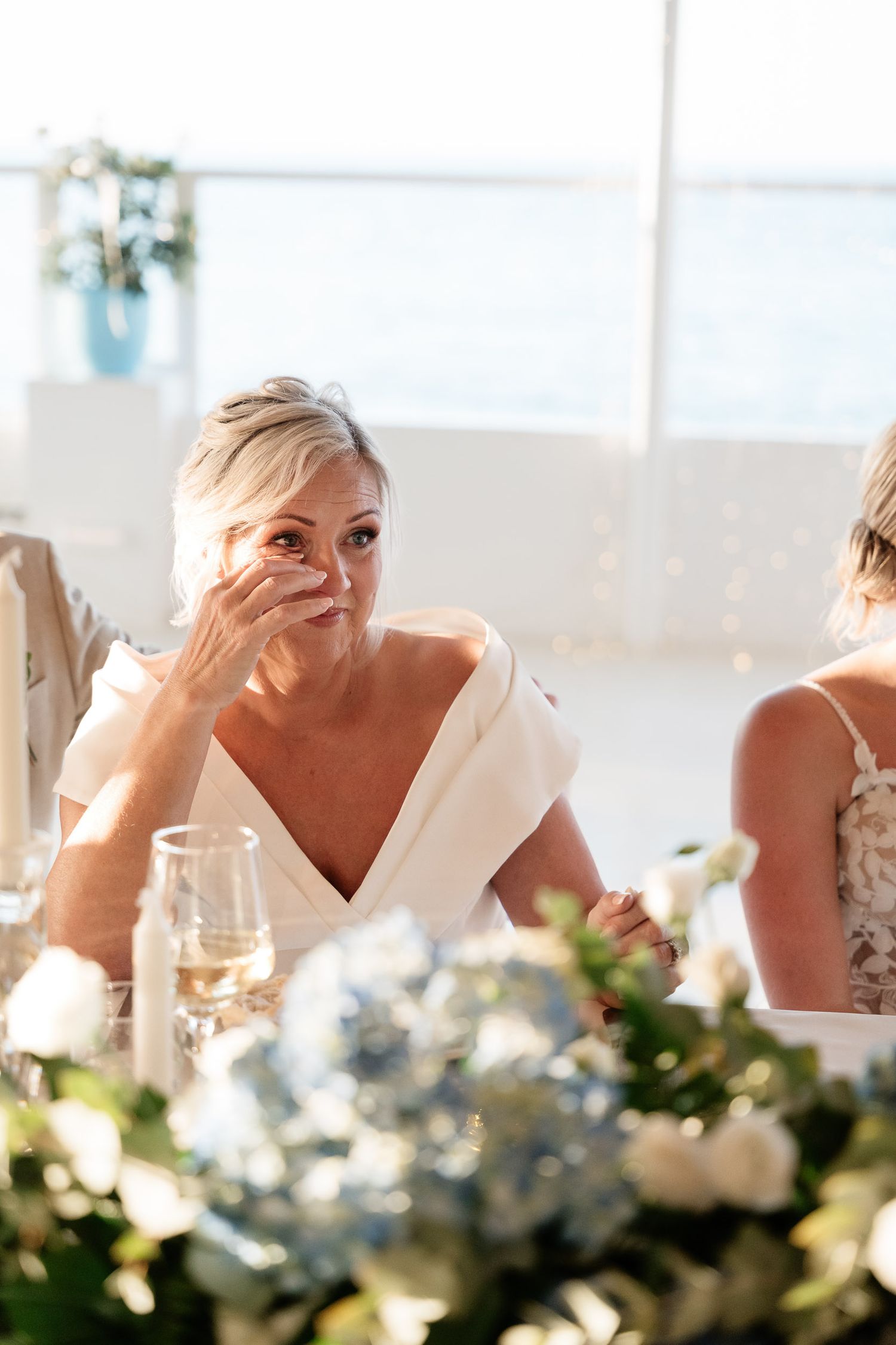 An emotional moment captured at a wedding reception as someone wipes away tears at an elegantly decorated table.