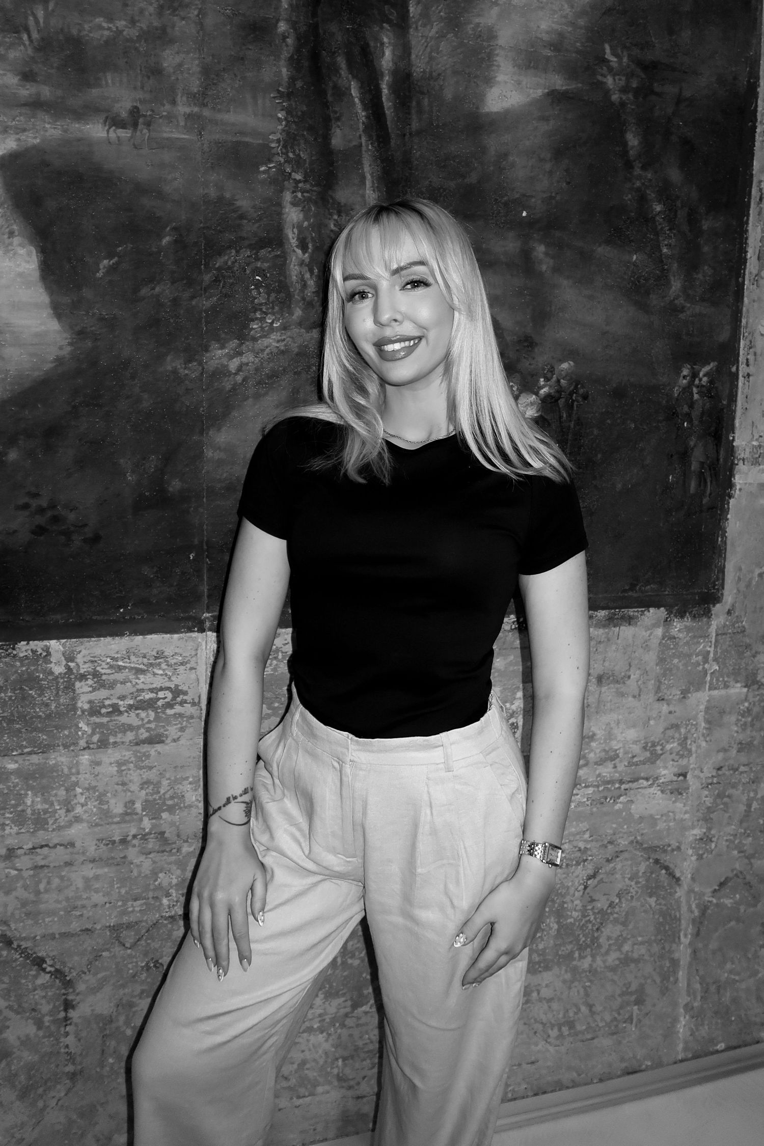 A sequence of black and white photos showing a figure in a black top and light pants against a textured wall.