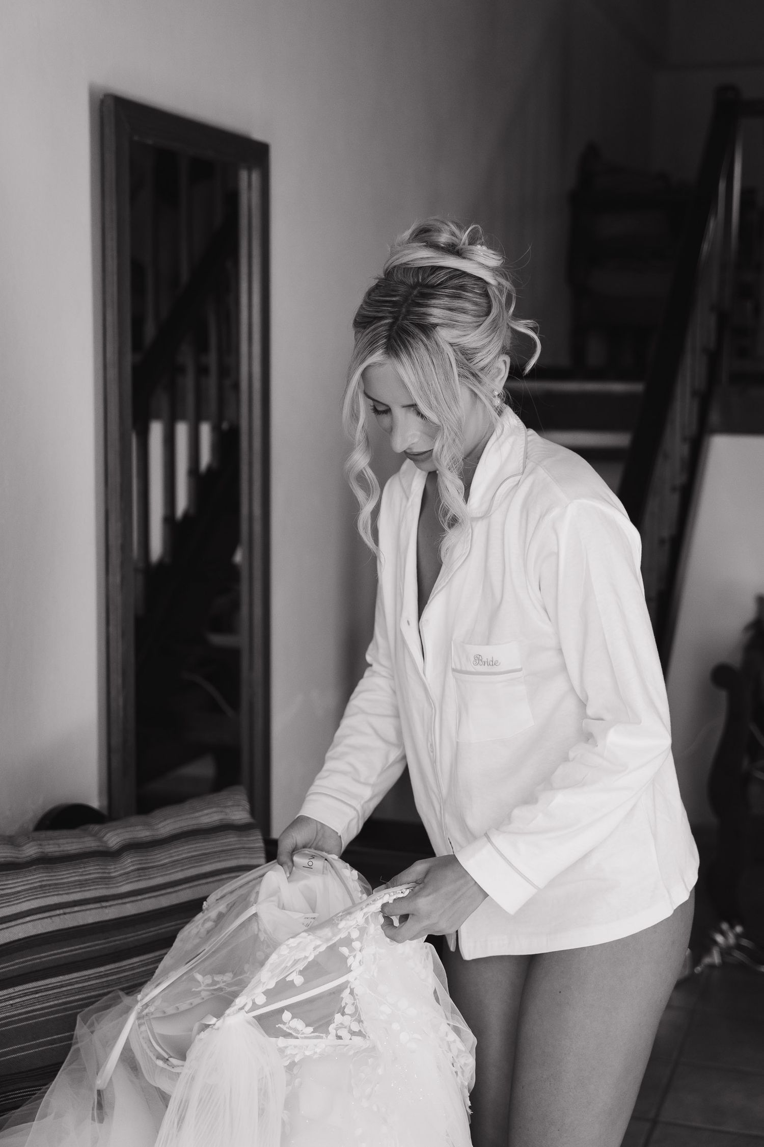 A figure in a white protective suit and mask carefully handles plastic bags while performing cleaning or sanitization tasks.