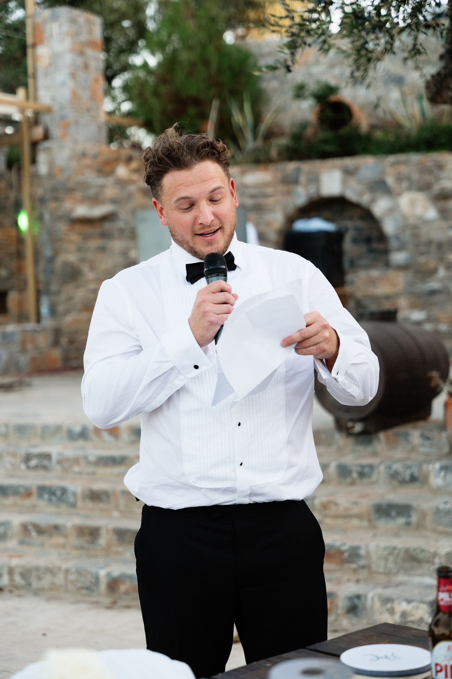 A person in formal attire with a bow tie is shown in a sequence of photos making animated expressions outdoors.