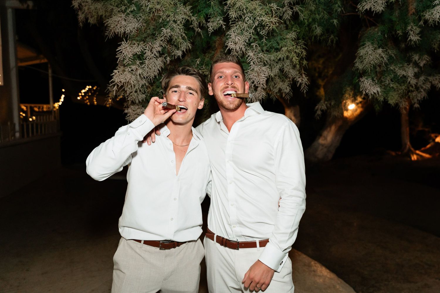 A group in white clothing poses and laughs together in an outdoor nighttime setting.