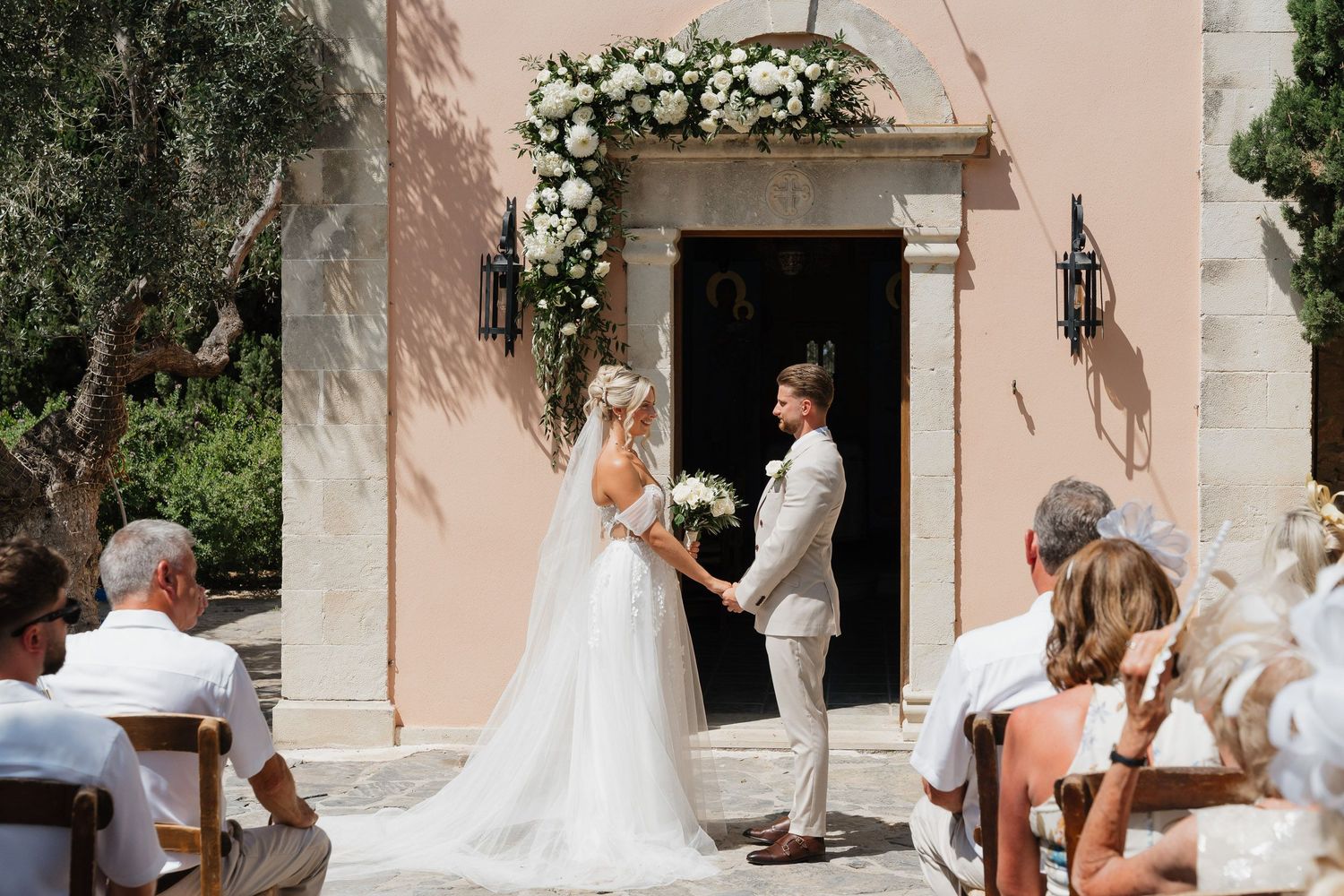 A series of wedding ceremony photos showing a couple at the entrance of a pink Mediterranean-style church.