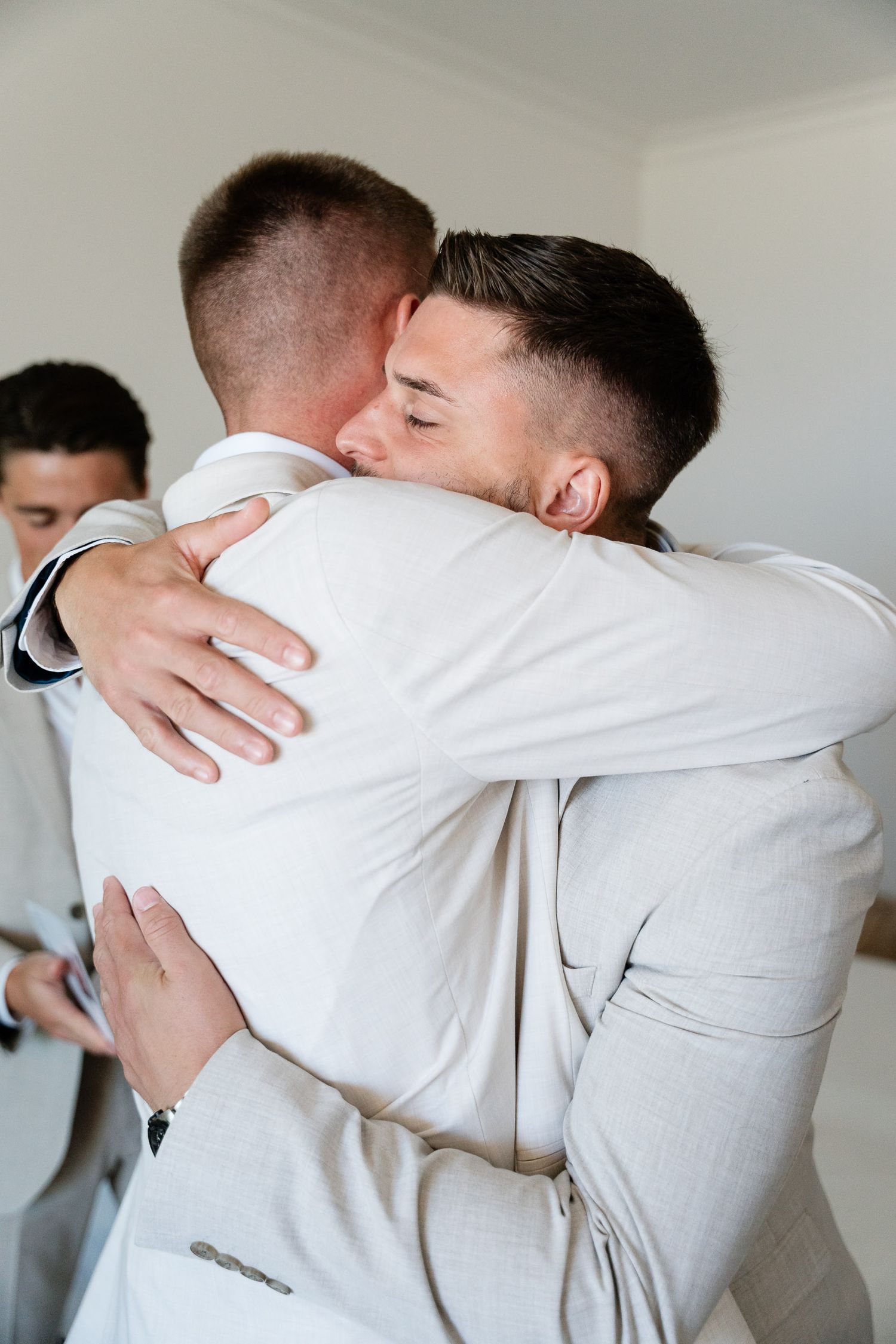 Two people in white clothing embrace in an emotional series of candid photographs showing a tender moment.