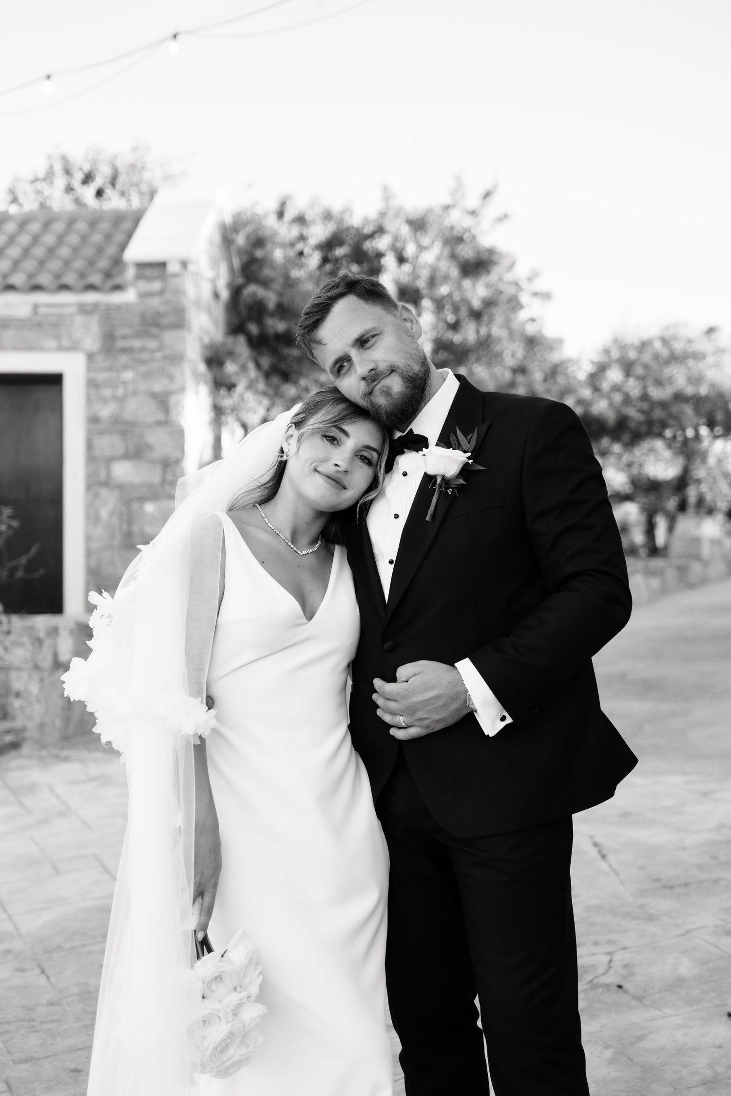 A bride and groom share playful candid moments in a series of black and white wedding photos outdoors.