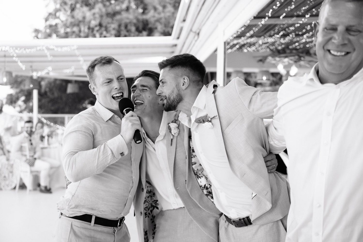 Black and white wedding photos showing joyful moments between couples and guests during an outdoor celebration.