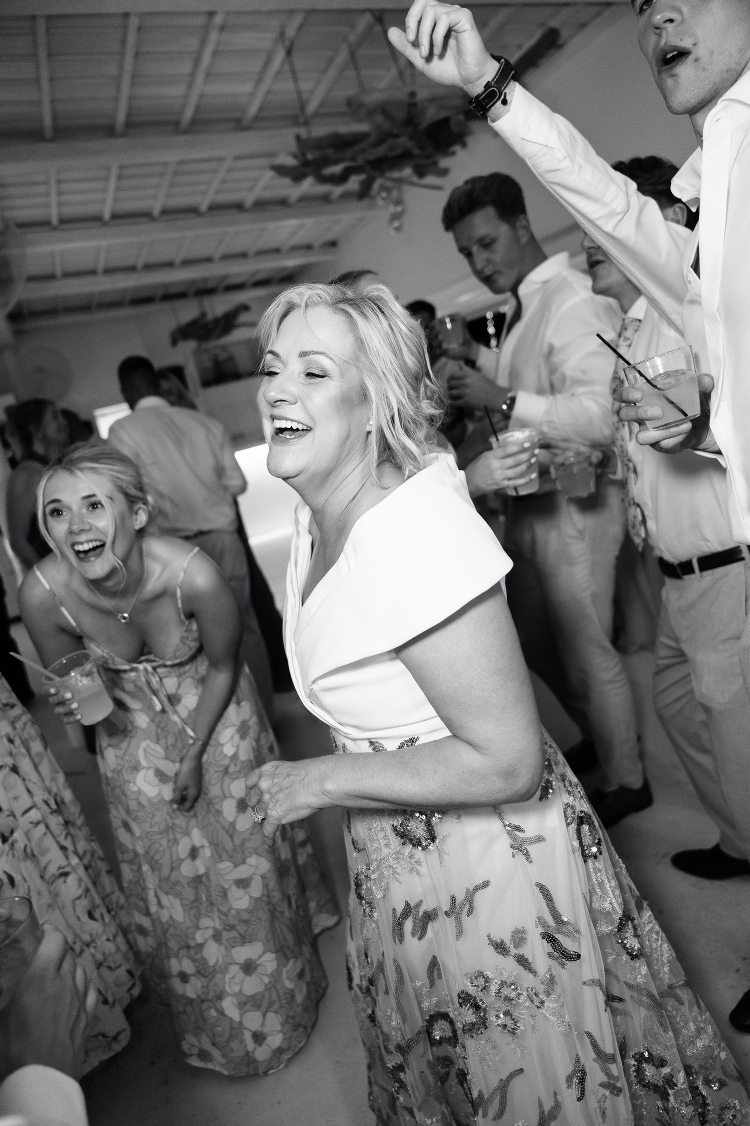 A series of black and white photos showing people dancing and laughing at a wedding reception.