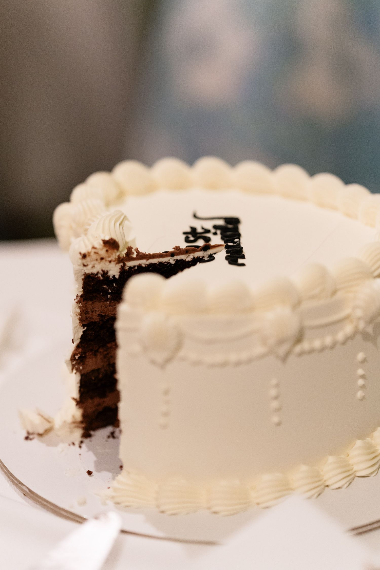 A white frosted chocolate layer cake with decorative piping shown in a sequence of slices being removed from the whole cake.