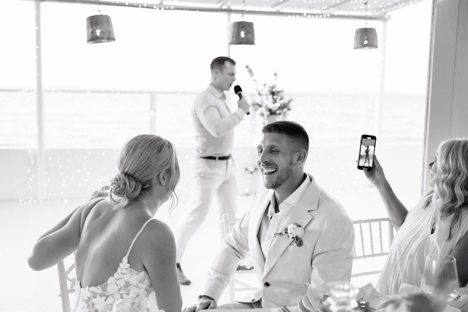 Wedding guests enjoying drinks and celebrating at an elegant white reception venue.