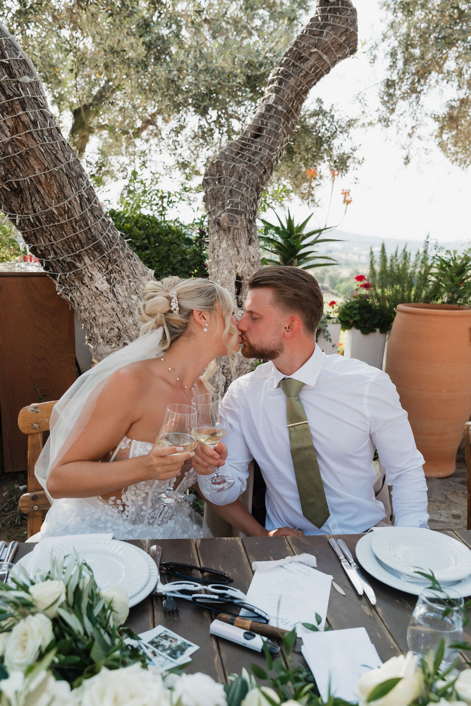 A romantic sequence of a couple sharing a playful moment while dining outdoors under olive trees.