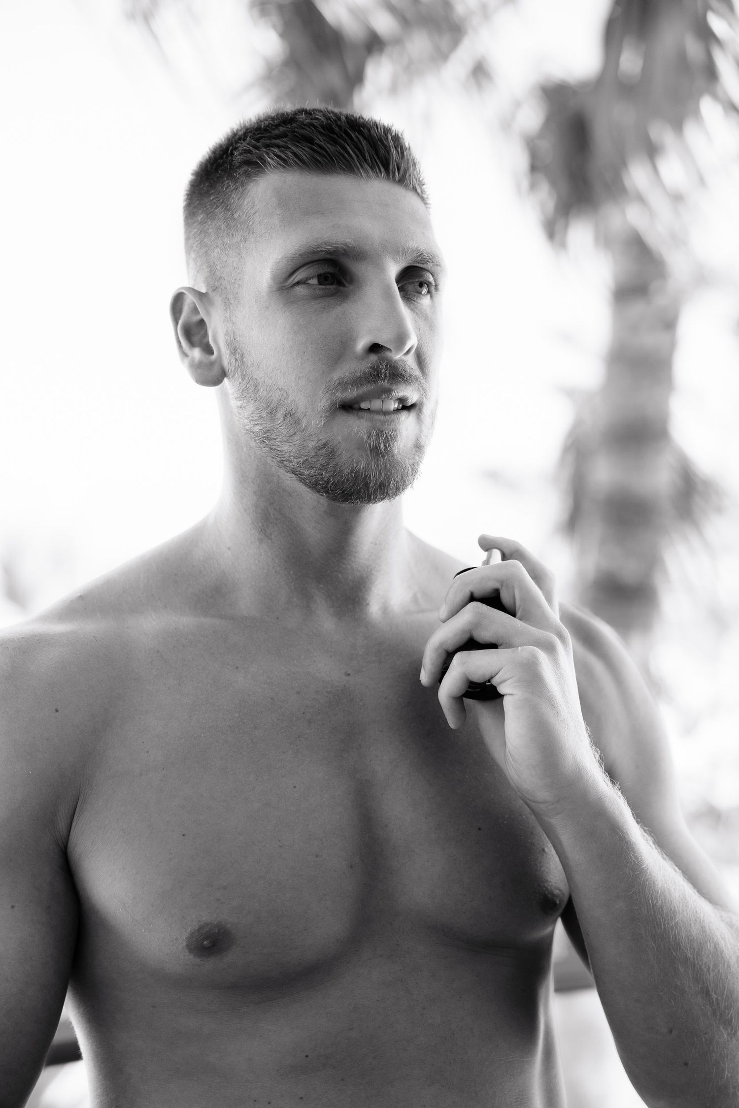 Black and white artistic portrait series showing a shirtless man in contemplative poses against a light background.