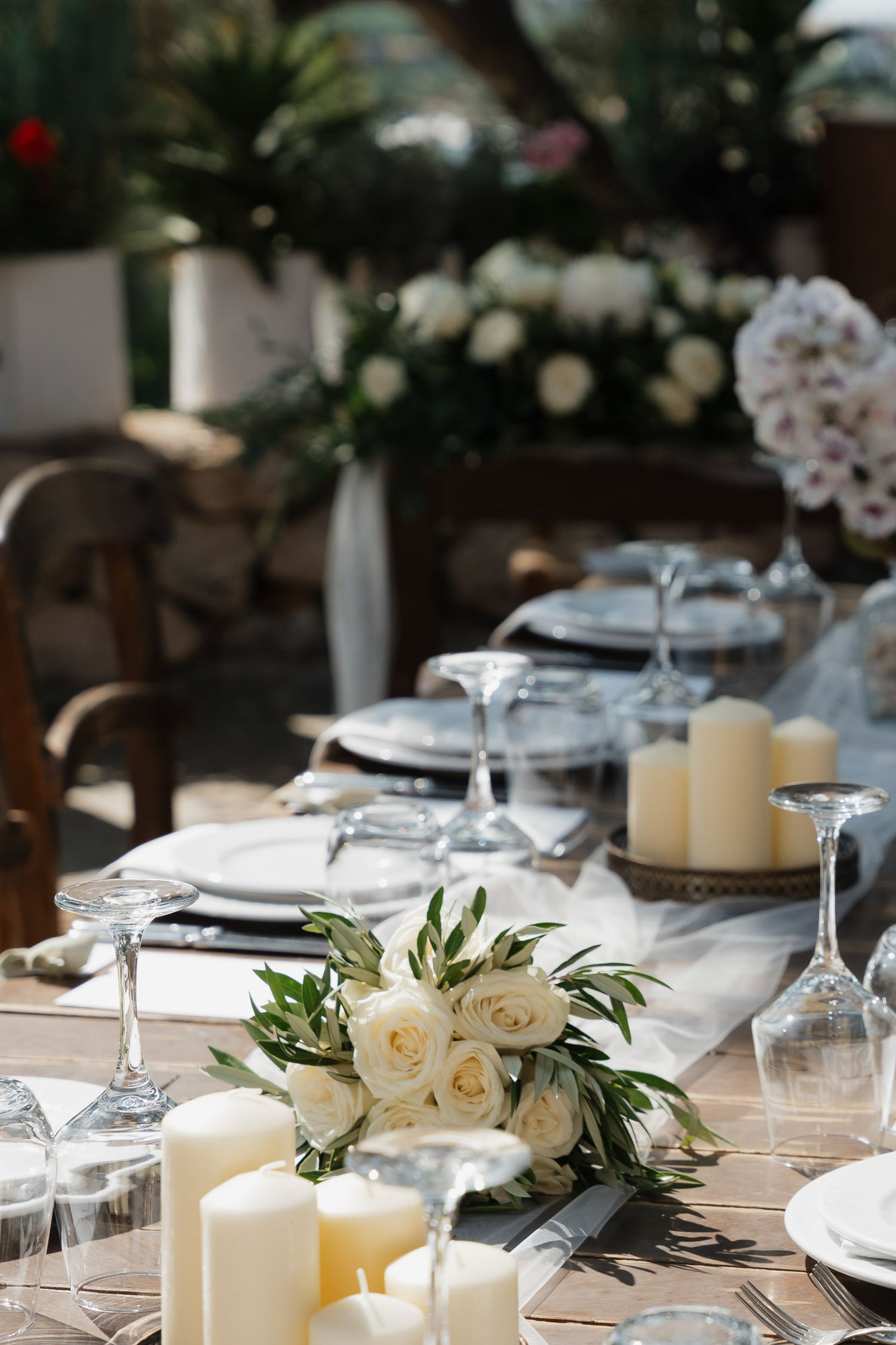 Elegant wedding table setting with white candles, roses, and delicate place settings in a modern minimalist style.