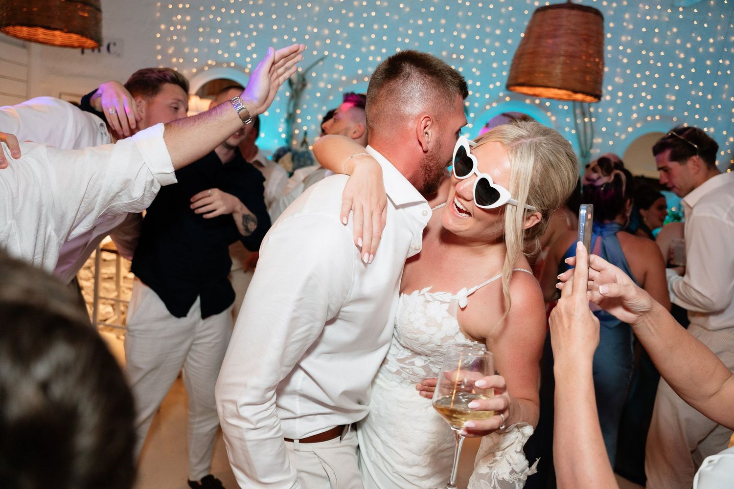 Romantic dance sequence at a wedding reception with couples embracing and dancing under soft lighting.