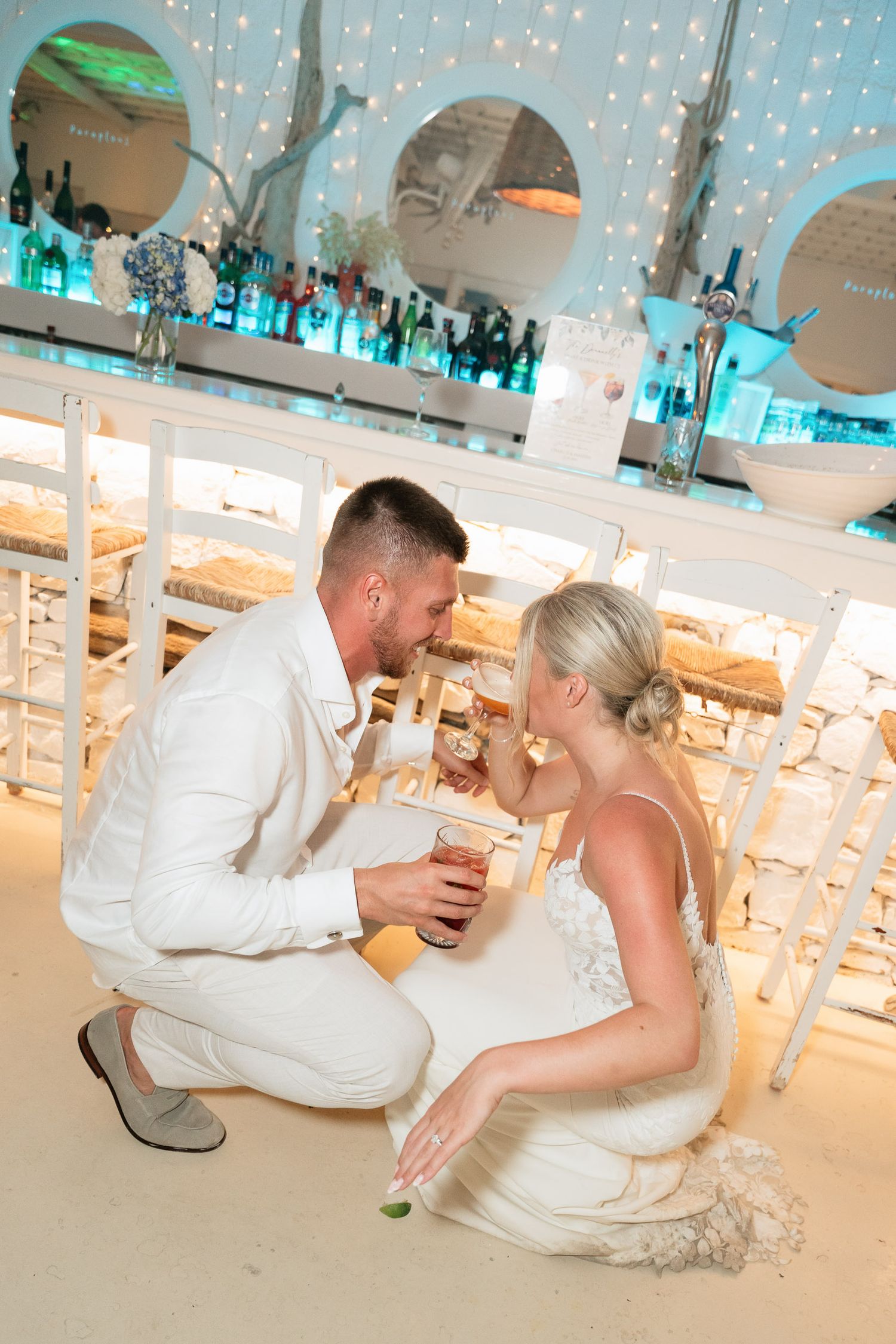 A couple in wedding attire shares playful moments on the dance floor during their reception celebration.