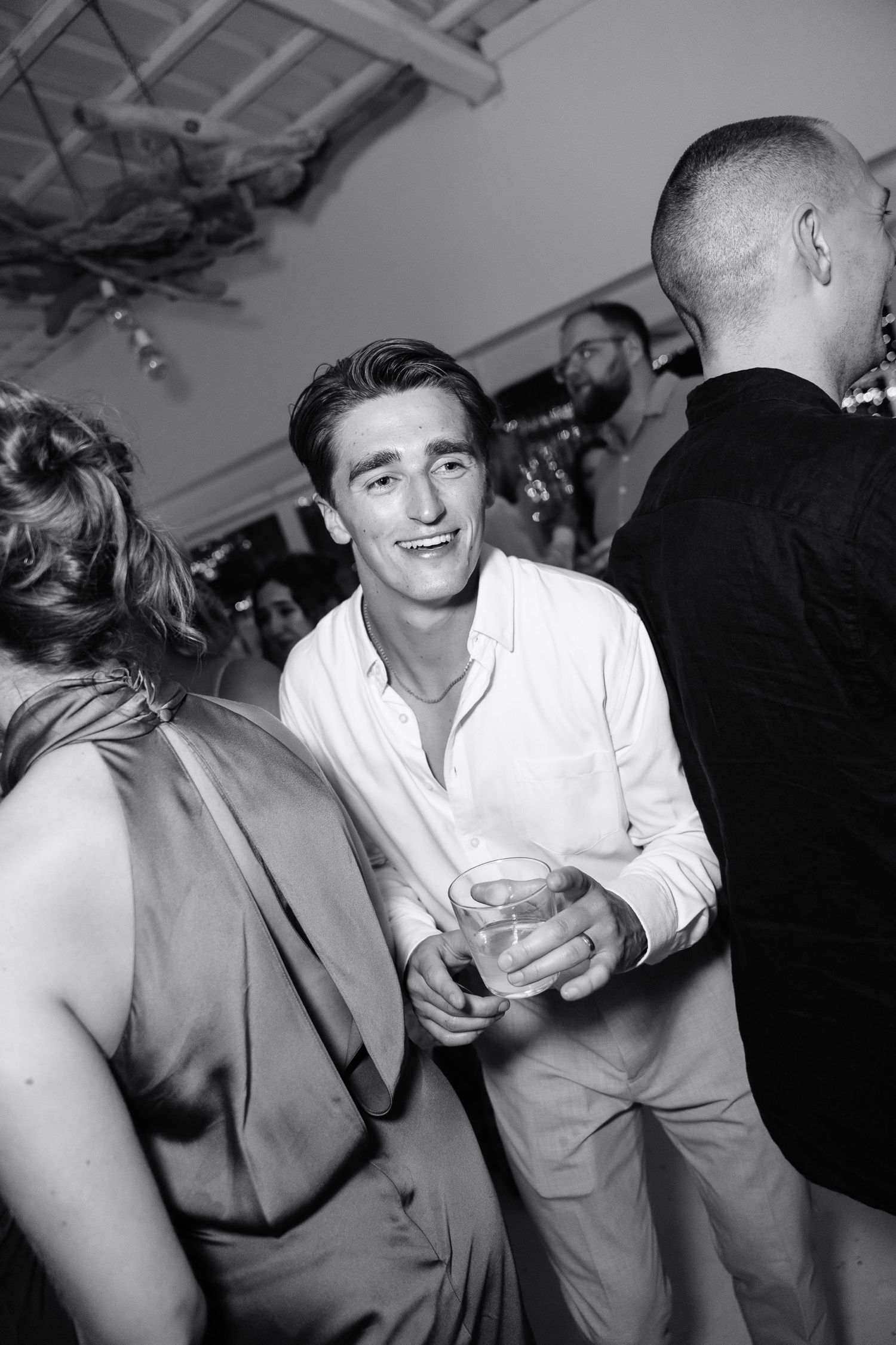 Black and white photos capturing candid moments of celebration and laughter at a wedding reception.