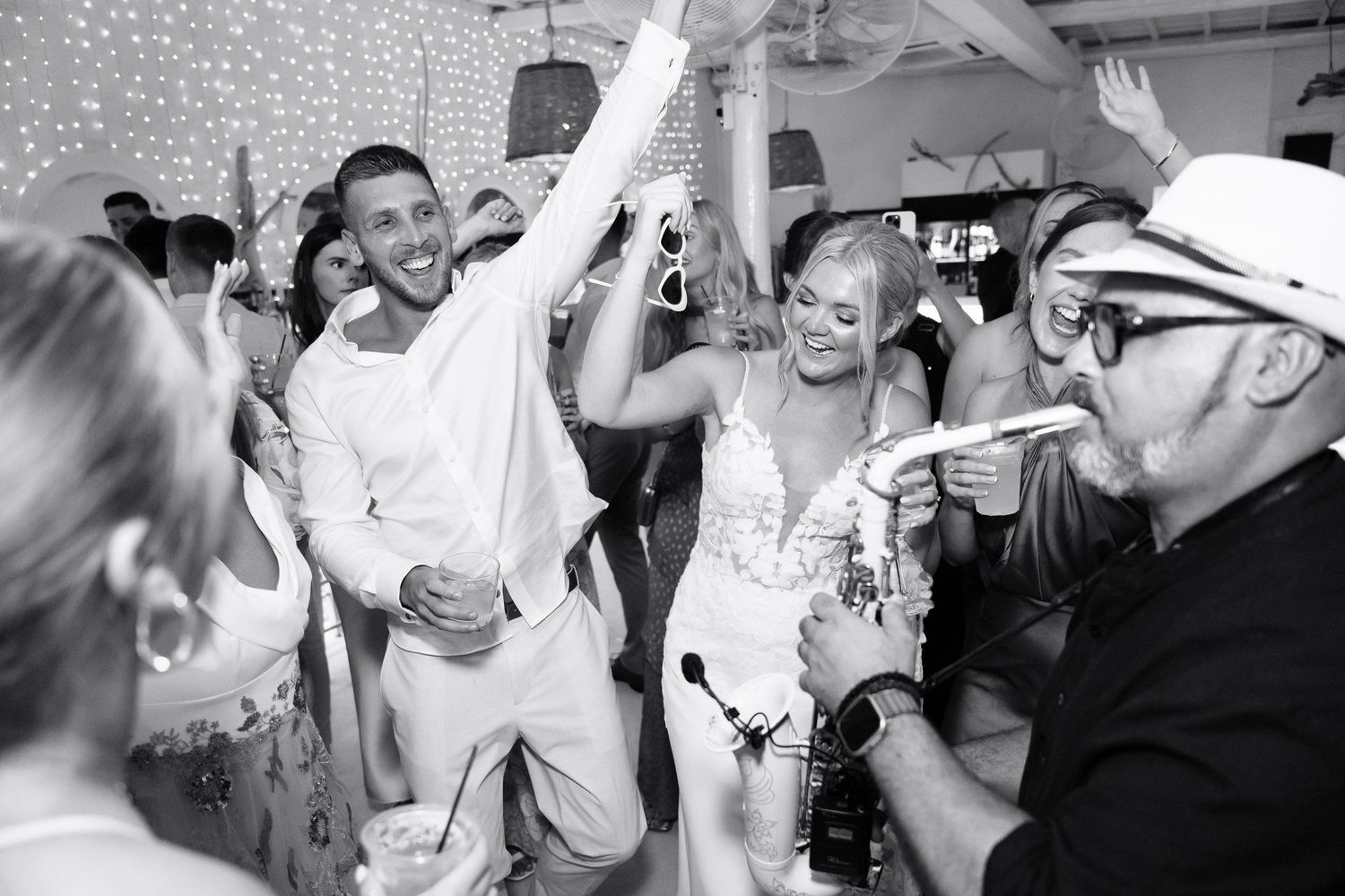 Wedding guests dance and celebrate together on a crowded dance floor at a reception party.