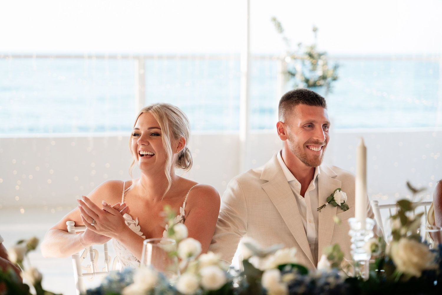 Wedding guests seated at an elegant reception table share joyful laughter during dinner celebration.
