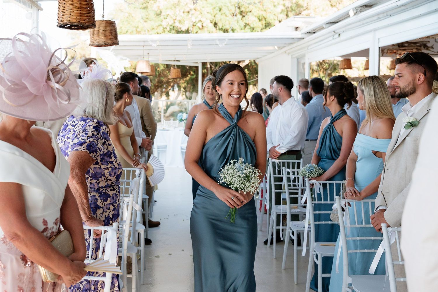 Wedding guests mingle and socialize during an outdoor reception with white chairs and decorative elements.
