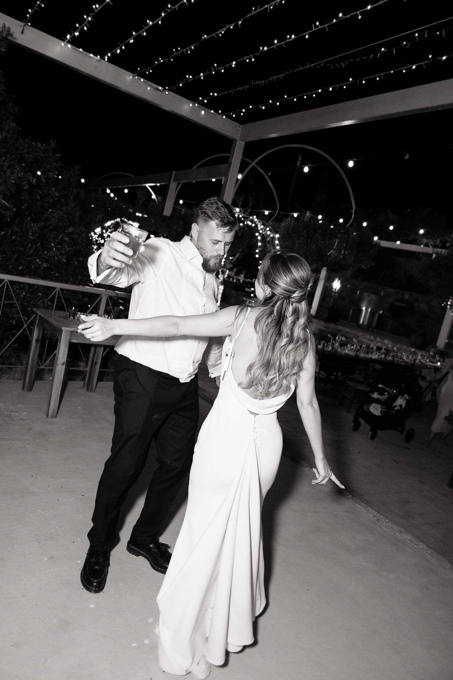 A couple in formal attire performs a romantic dance dip move on an illuminated dance floor at a wedding reception.