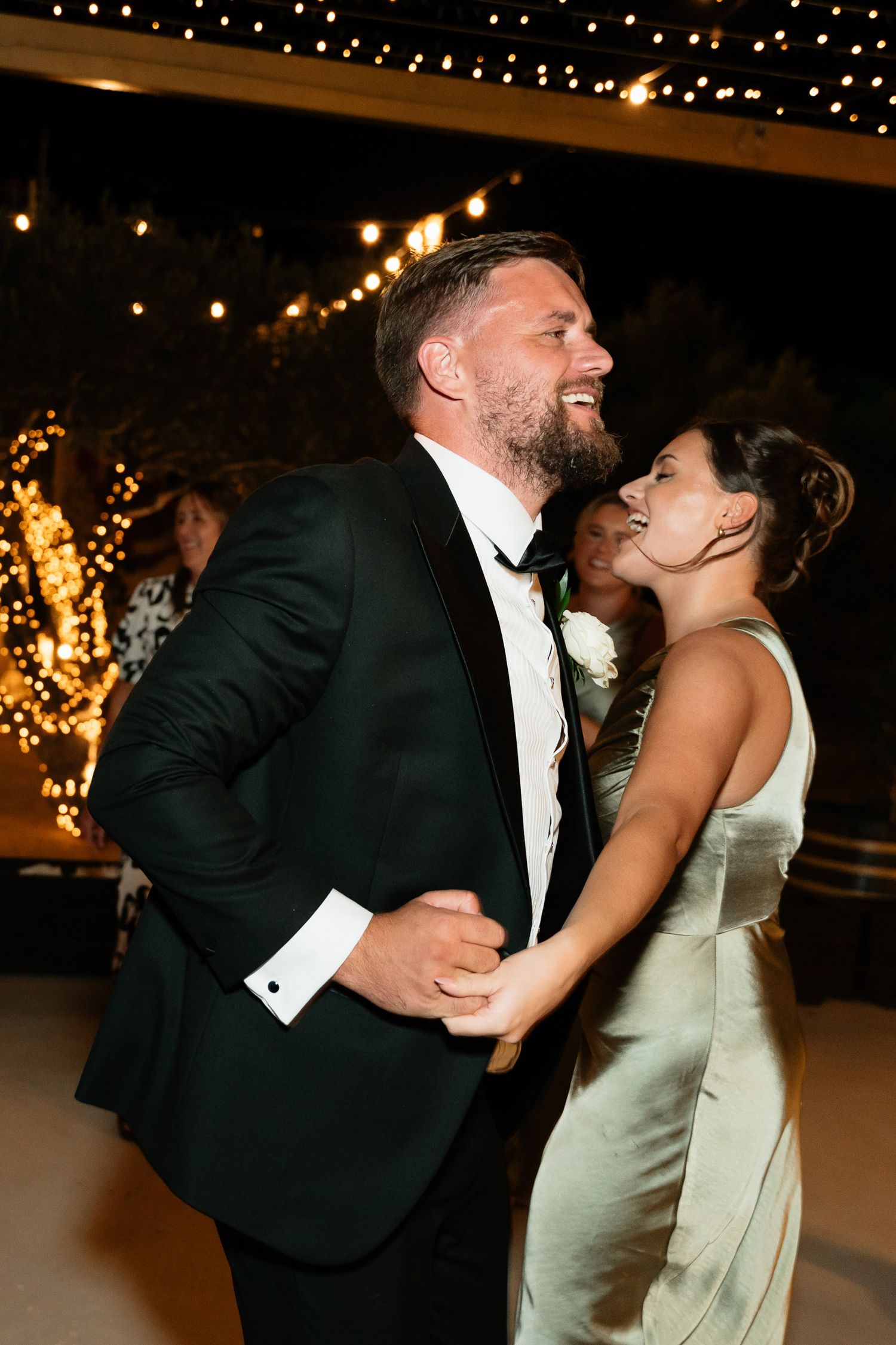A romantic first dance between newlyweds under twinkling lights at their wedding reception.