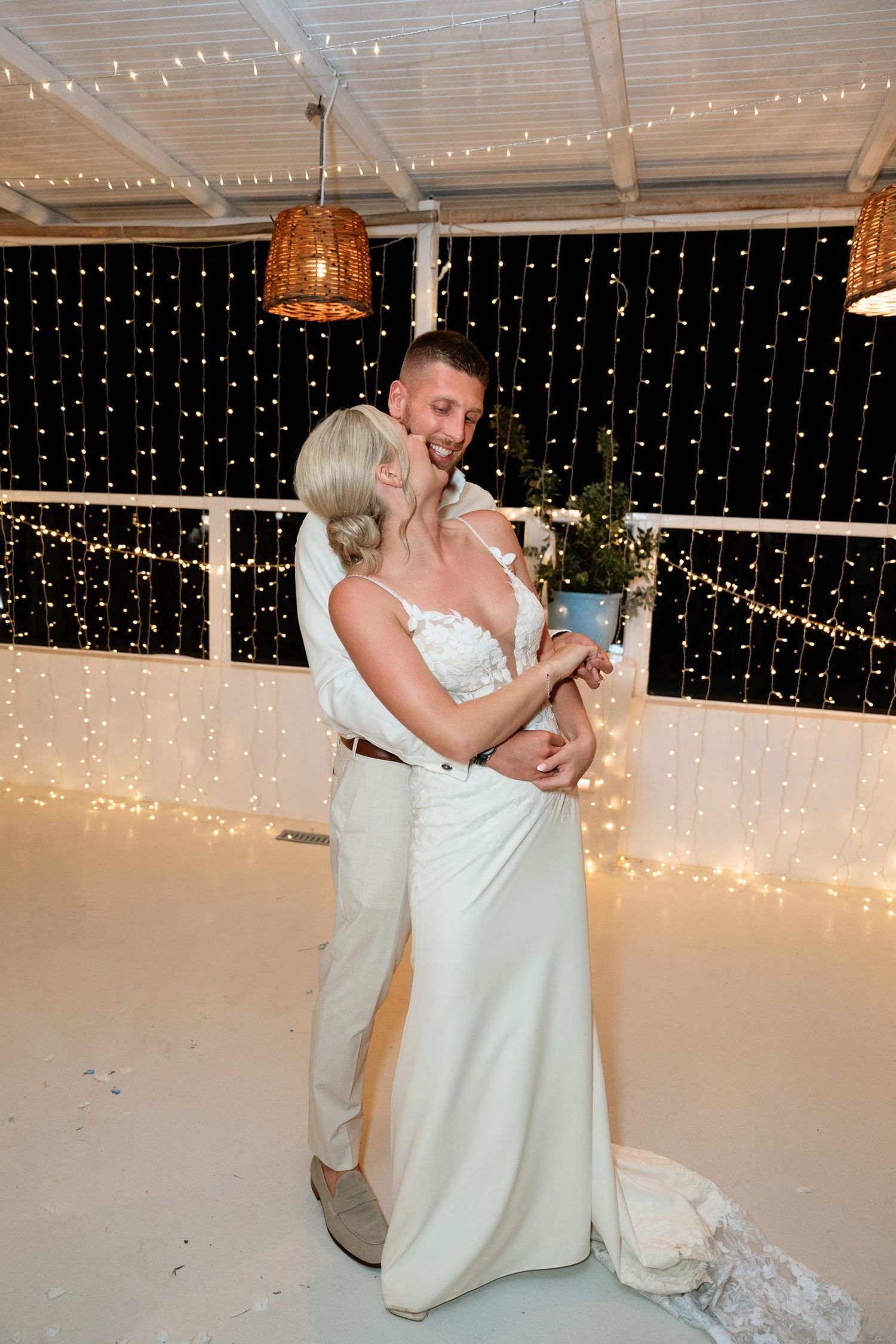 Wedding couple shares a romantic dance moment under twinkling fairy lights at their reception.