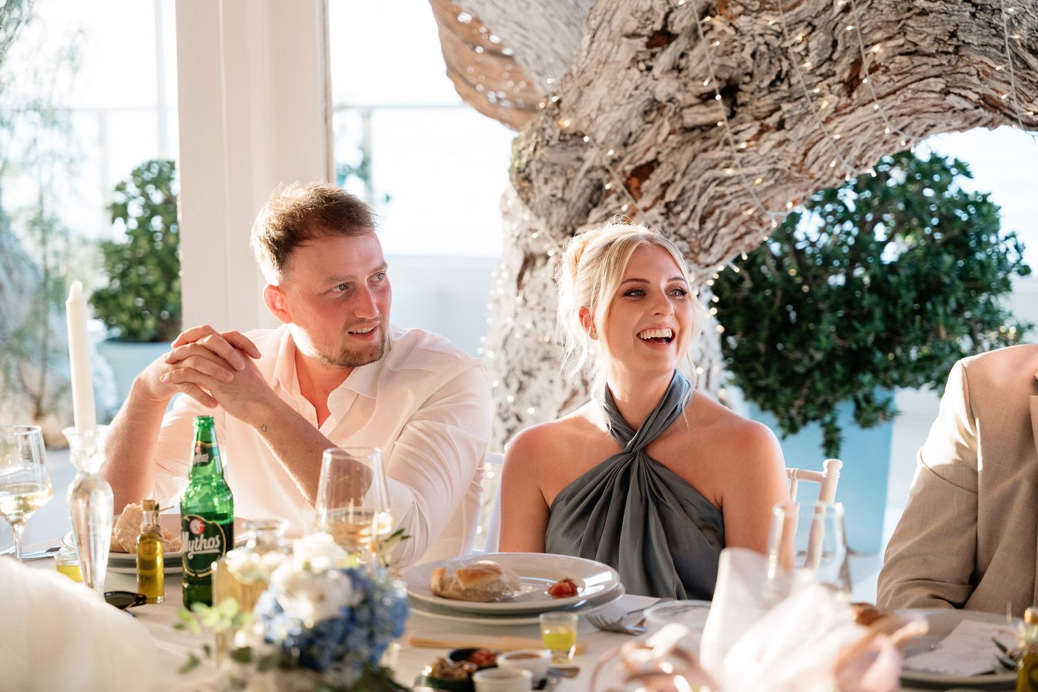 Wedding guests share joyful laughter during a reception celebration at an elegant indoor venue.