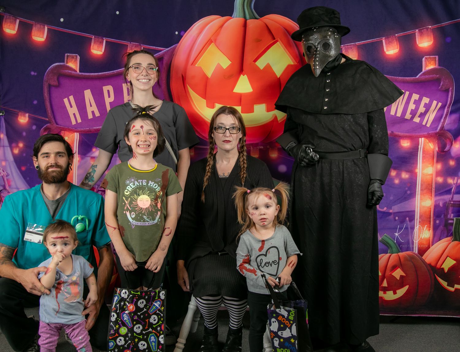 Halloween themed photo with a large glowing pumpkin backdrop and people in costumes.