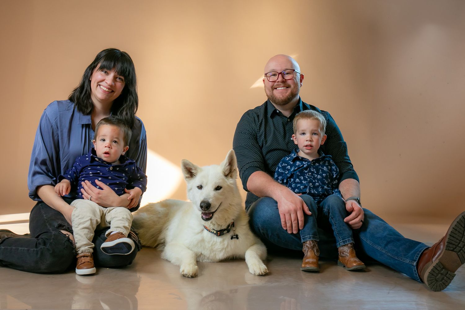 A group relaxing on the floor at home with a white fluffy dog in a casual indoor photo series.