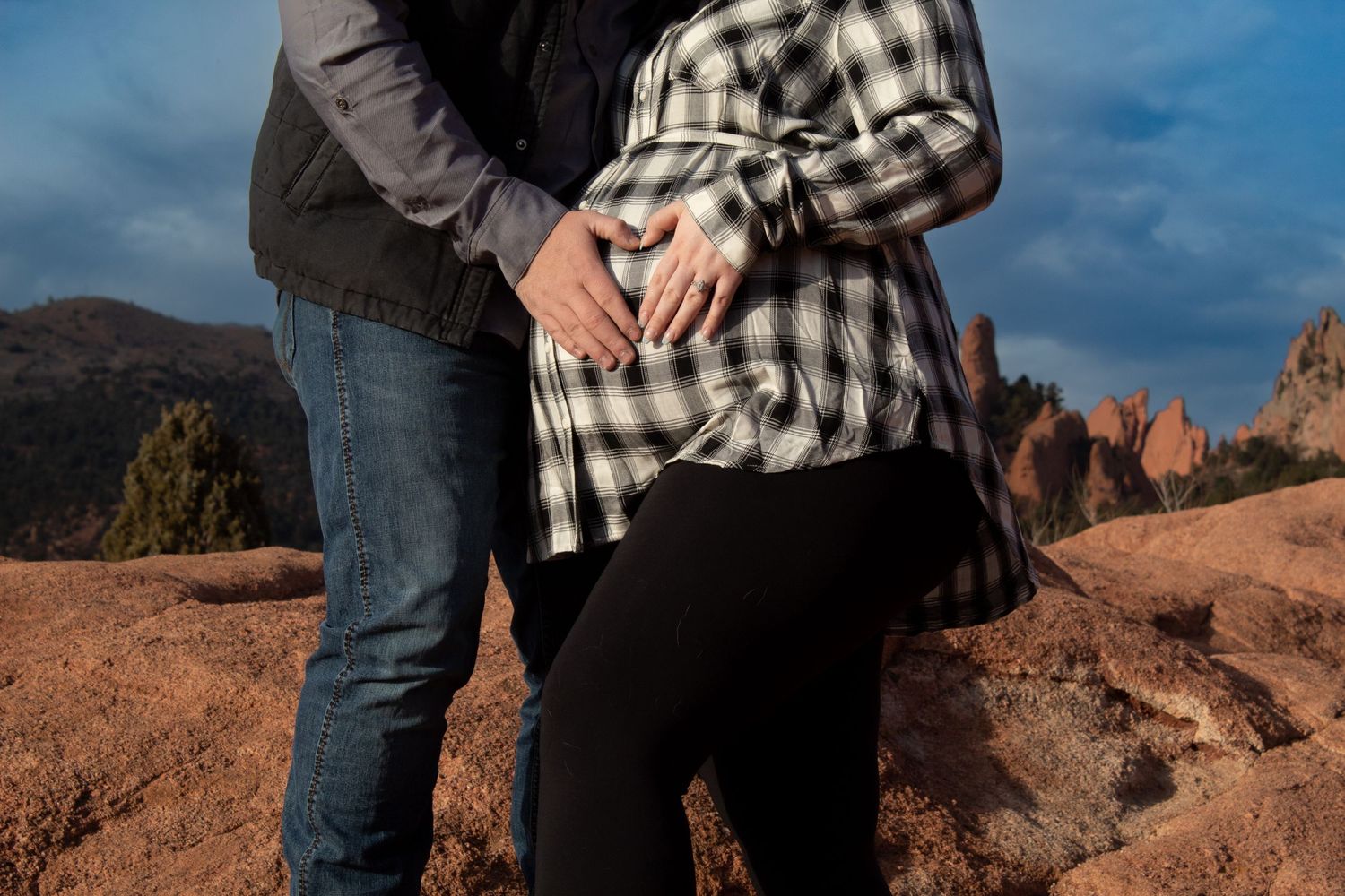 A couple embracing at sunset against a rocky desert landscape backdrop.