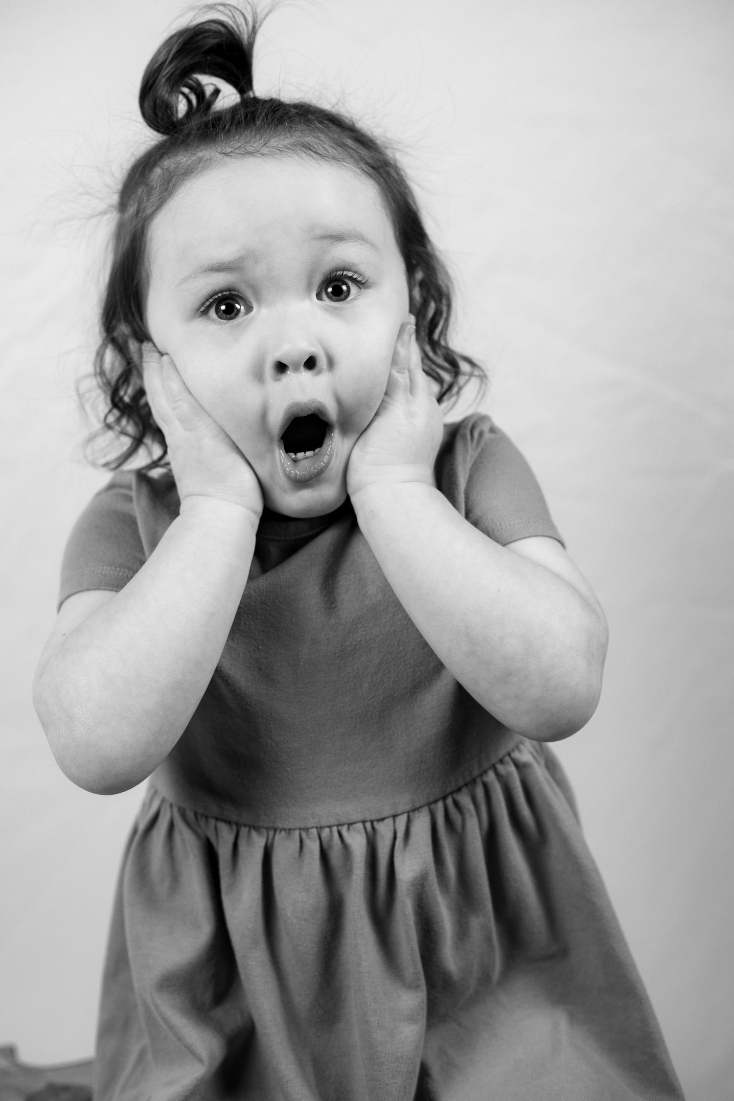 Black and white portrait series of young child making silly expressions.