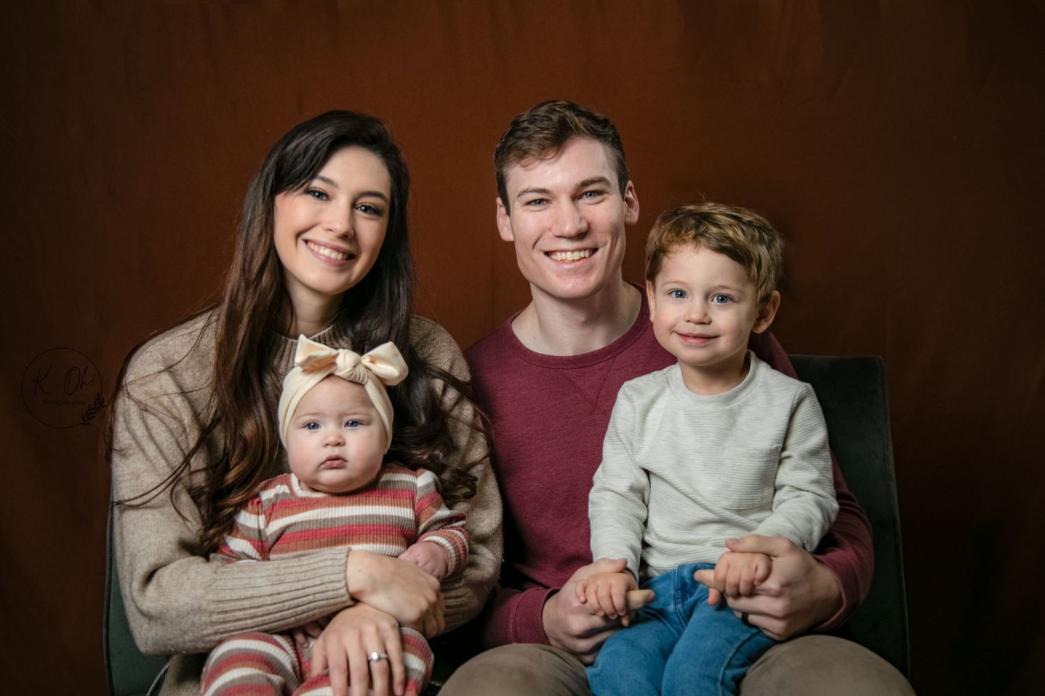Studio family portrait session against dark brown background.