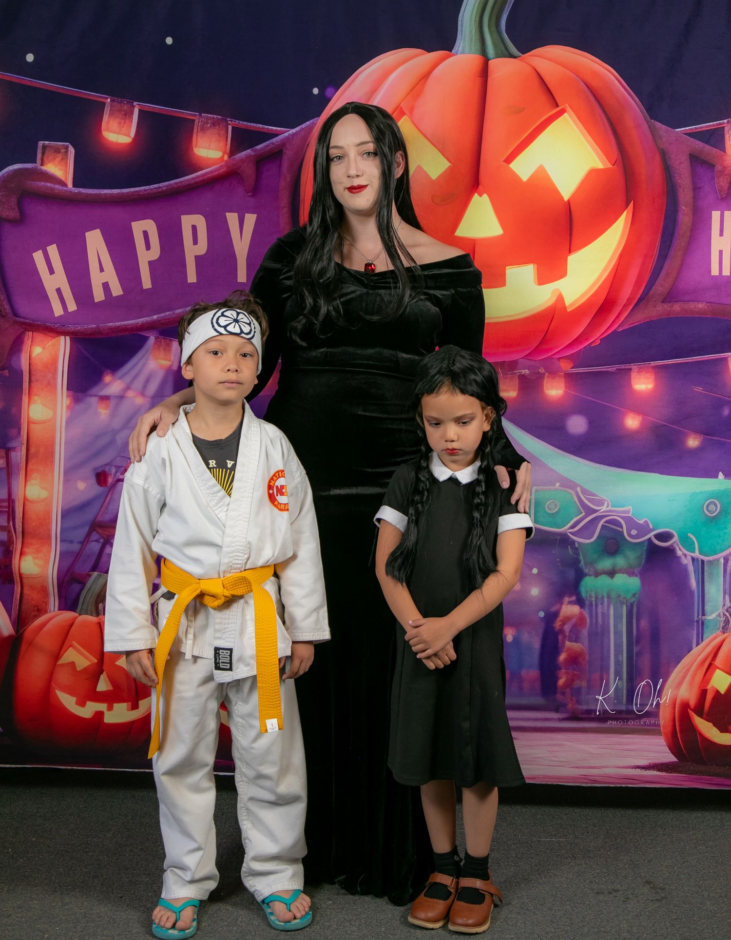 Halloween portrait with a spooky illuminated pumpkin backdrop and gothic themed costumes.