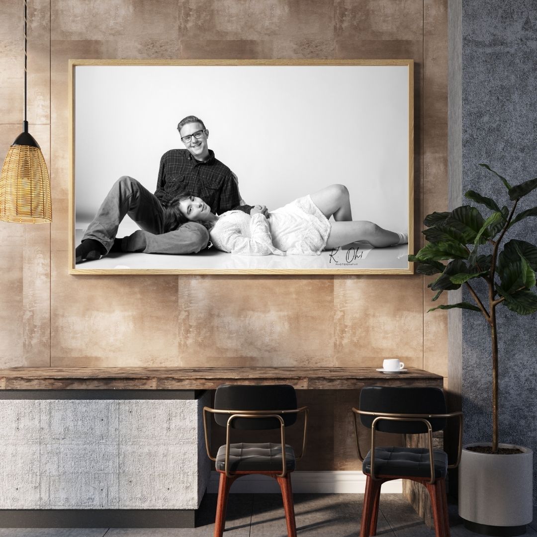 Wide horizontal photo wall display featuring multiple black and white framed photographs mounted on a textured beige wall.