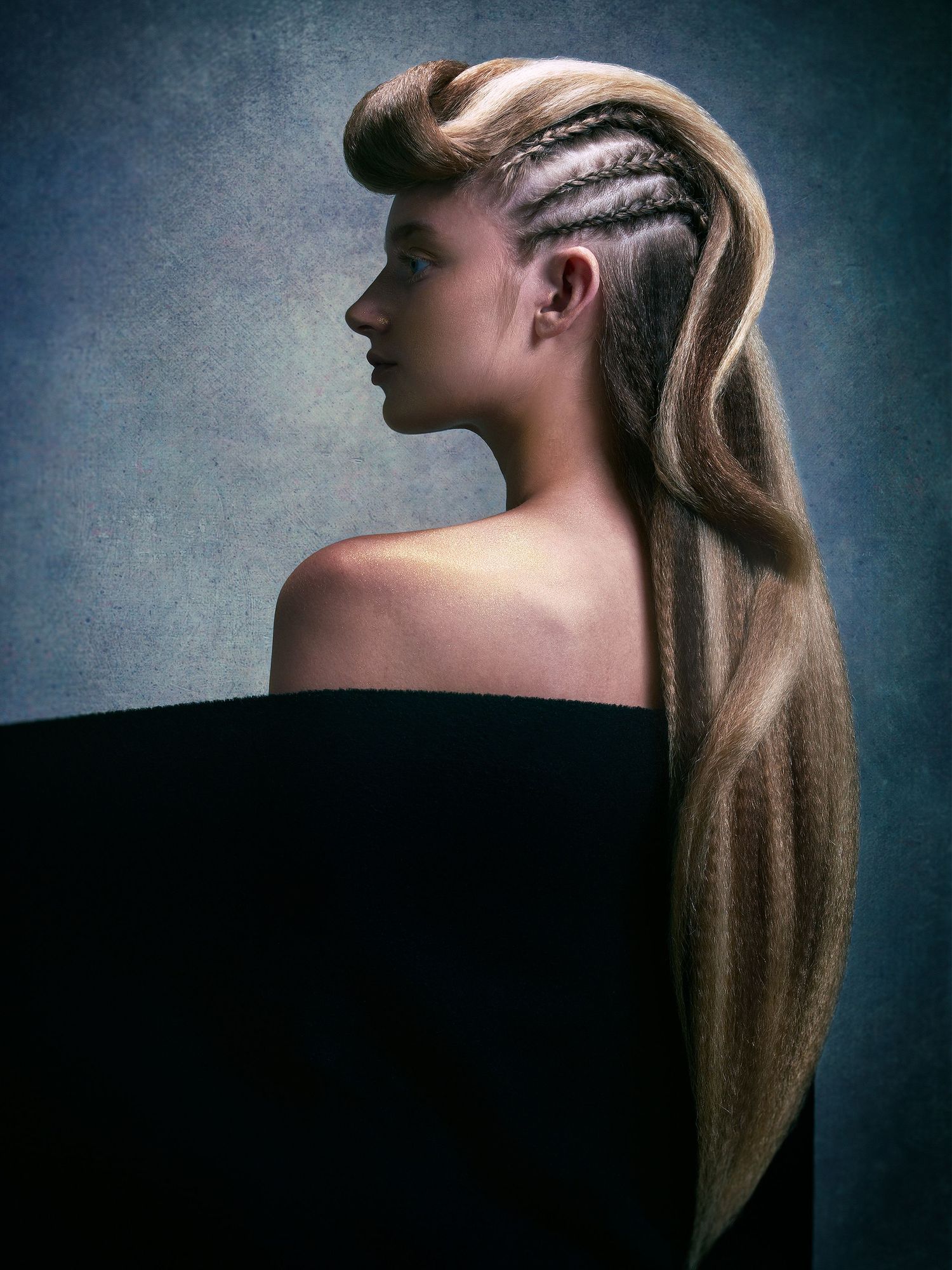 Side profile view of an elegant hairstyle featuring long blonde hair with intricate braided cornrows on one side.