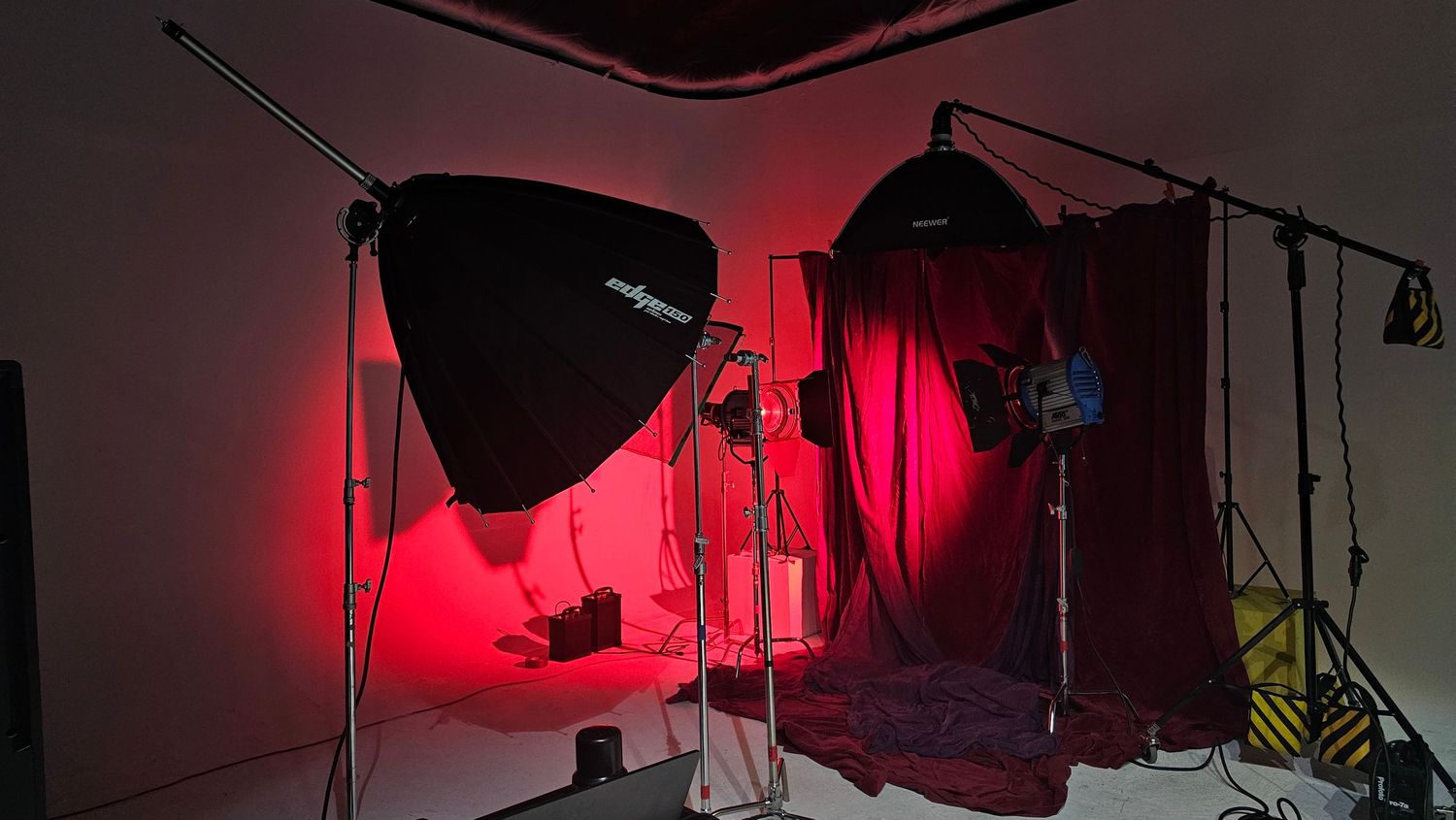 Dark photo studio setup with red lighting and softboxes creating moody atmosphere.