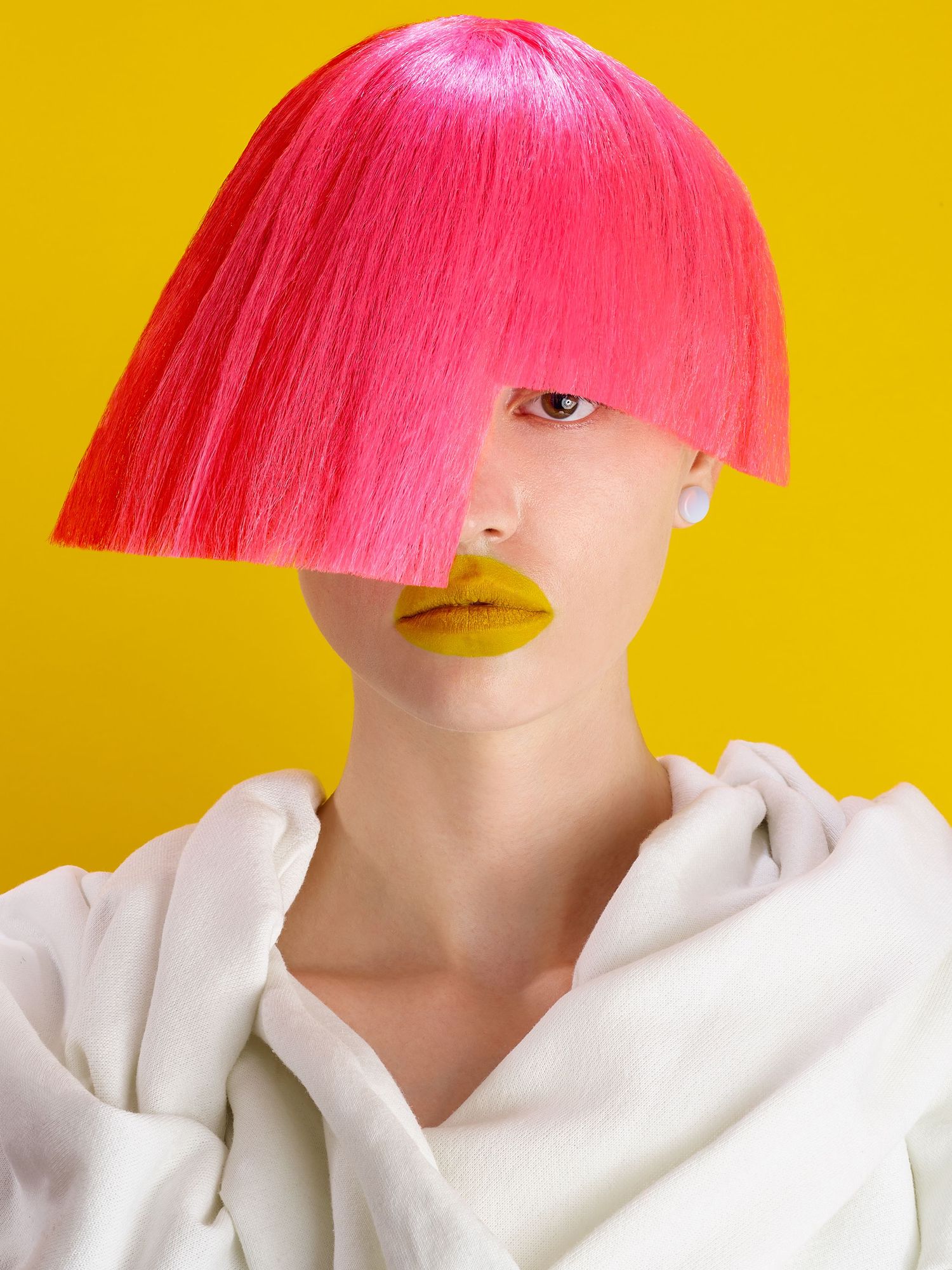 Fashion beauty portrait with vibrant pink geometric bob haircut and yellow lipstick against bright yellow background.